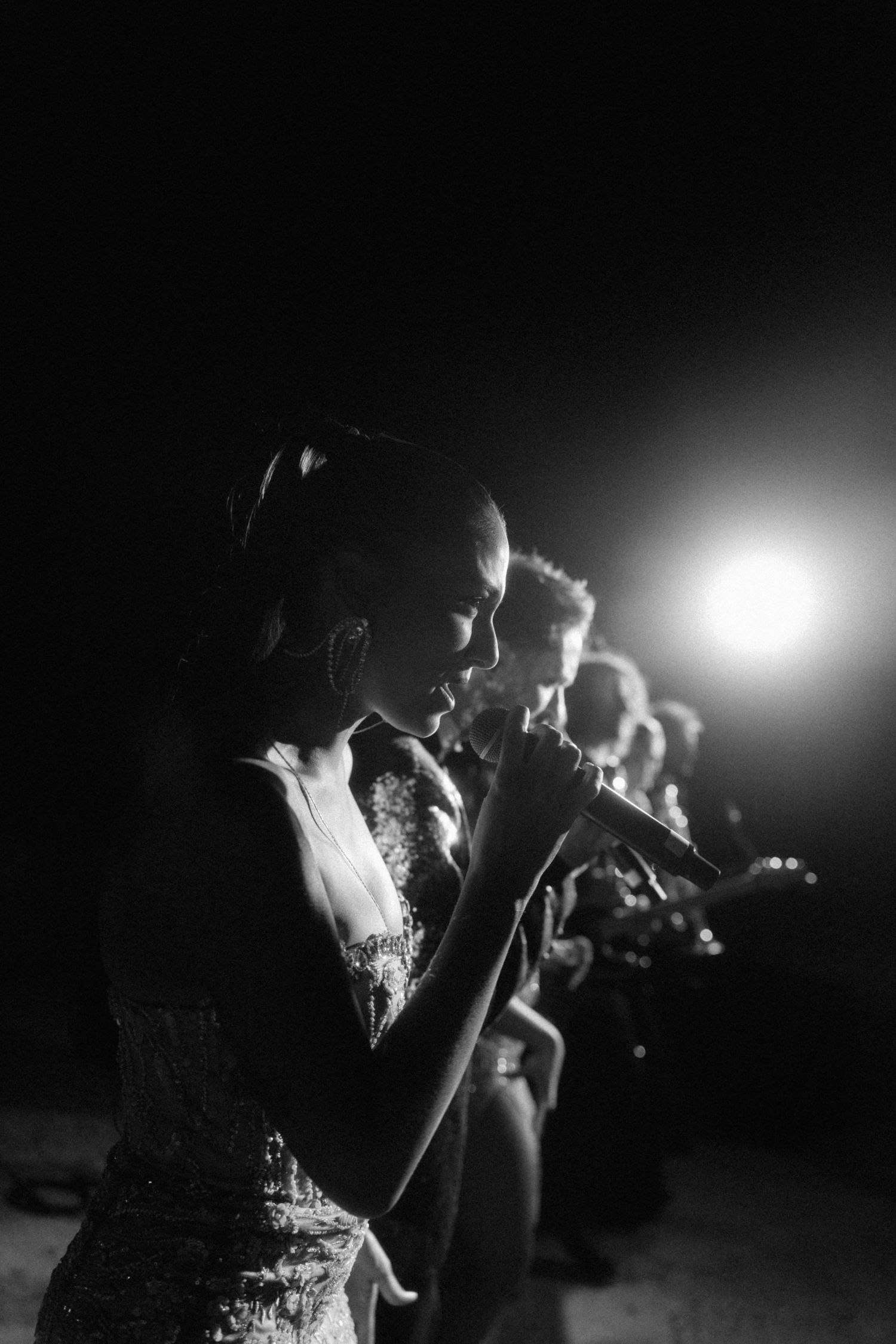 Black and white photo of female vocalist performing with band at elegant nighttime wedding reception.