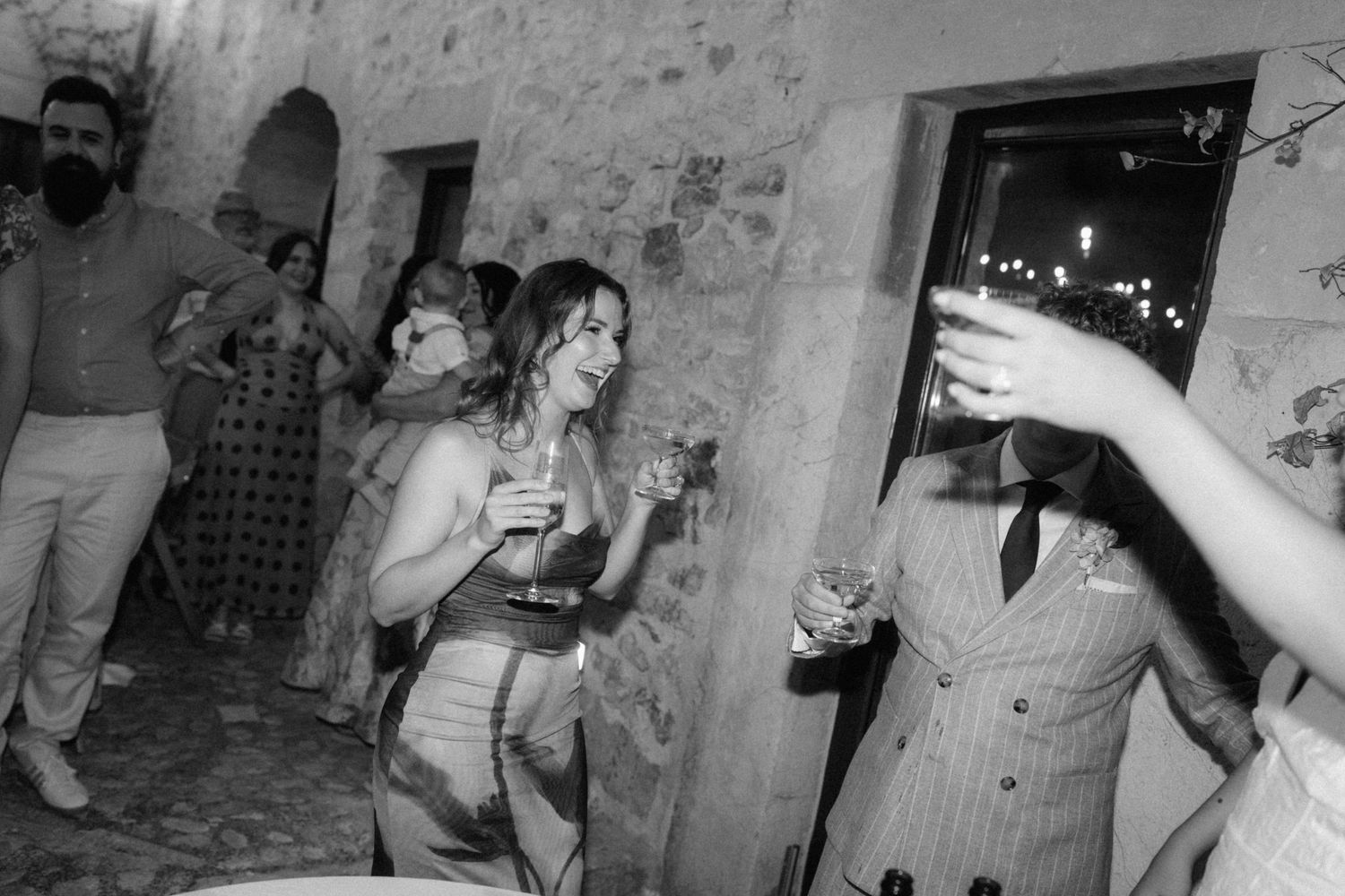 Black and white photo of guests dancing and celebrating at an outdoor evening wedding reception party.