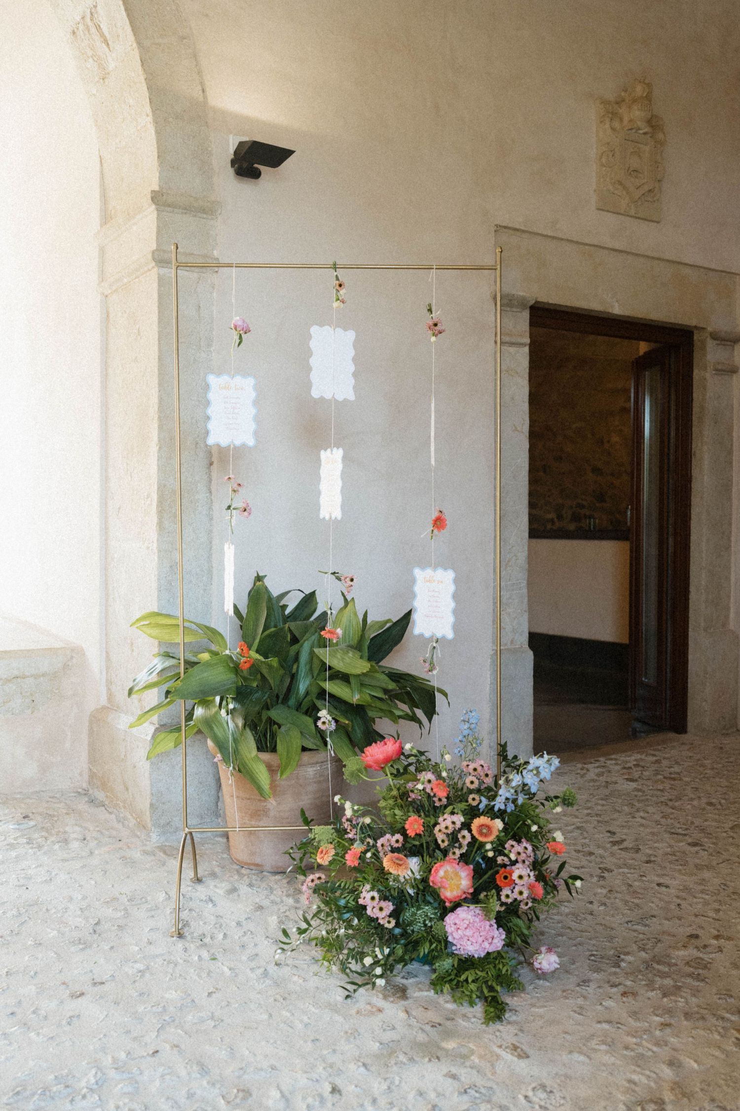 Wedding seating chart display with floral arrangements in a charming stone venue entrance.