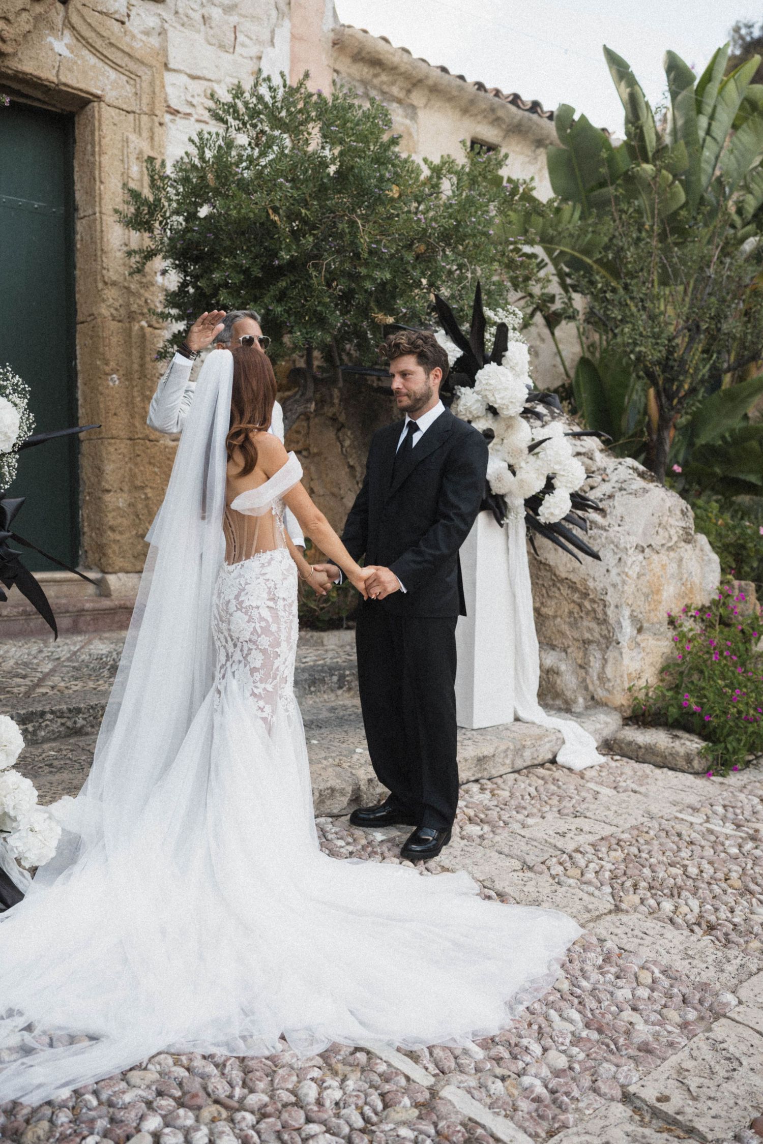Bride and groom holding hands at outdoor wedding altar with white floral decorations.