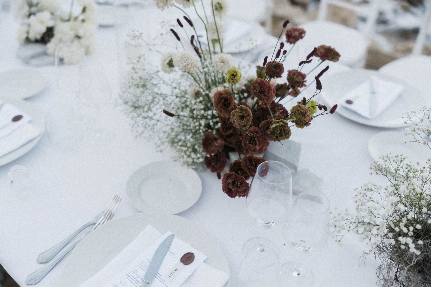 Elegant wedding table setting with white roses, baby's breath centerpiece, crystal glasses and place settings.