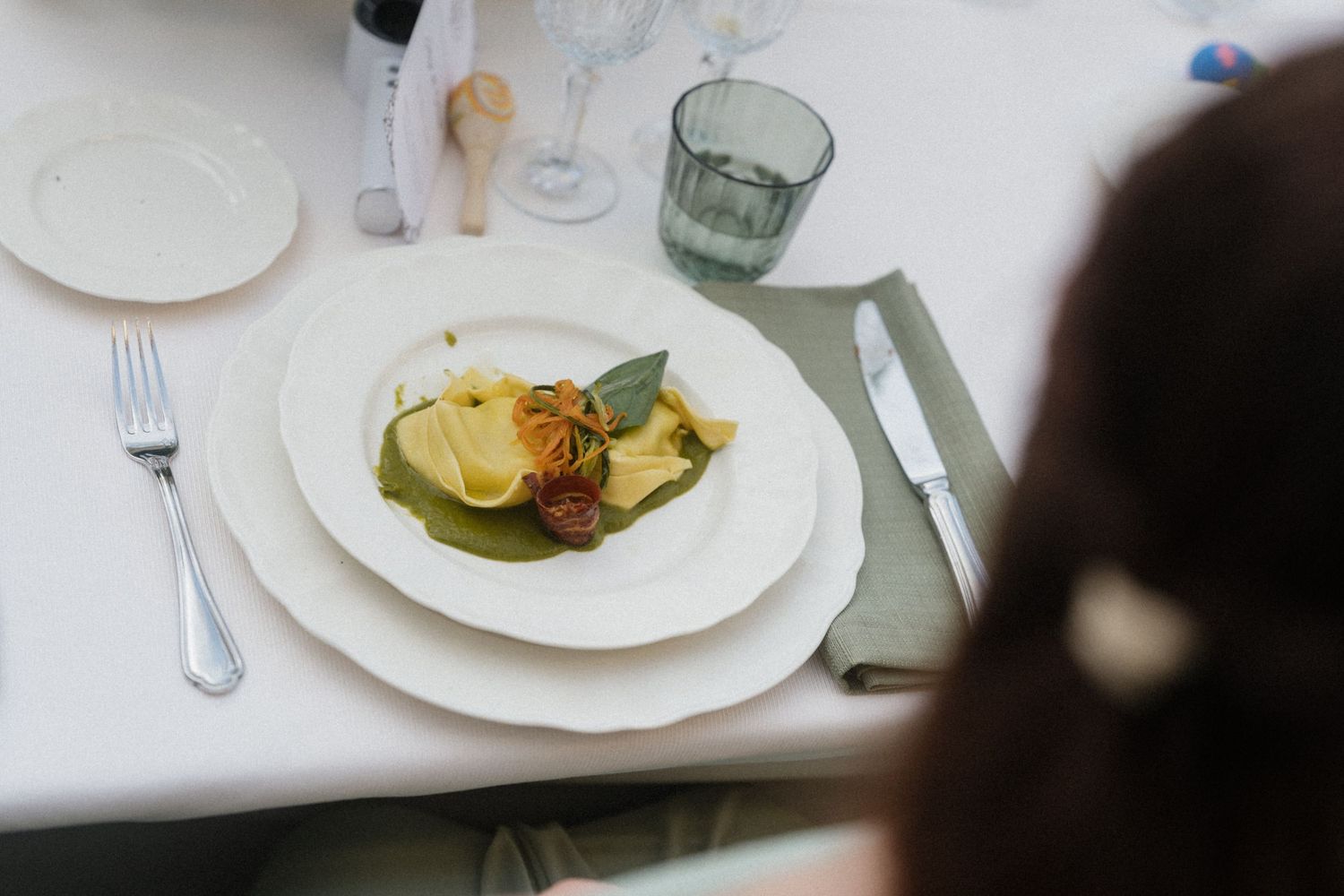 Elegant wedding reception plate featuring colorful gourmet appetizers on white china with green linen napkin.
