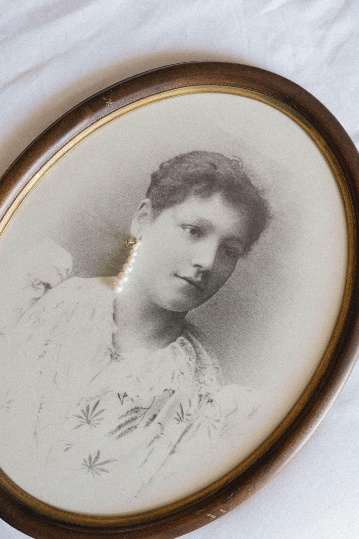 Vintage oval-framed black and white portrait photograph of a young woman in antique brass frame.