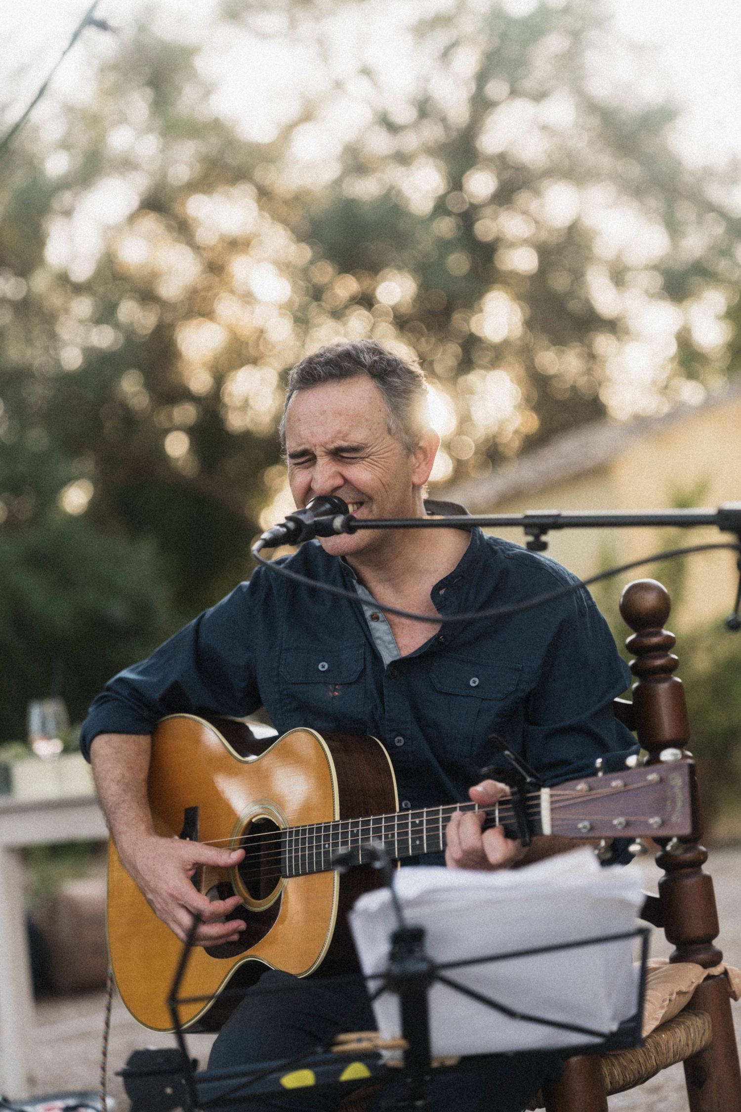 Male guitarist performing live acoustic music outdoors at a wedding reception at golden hour.