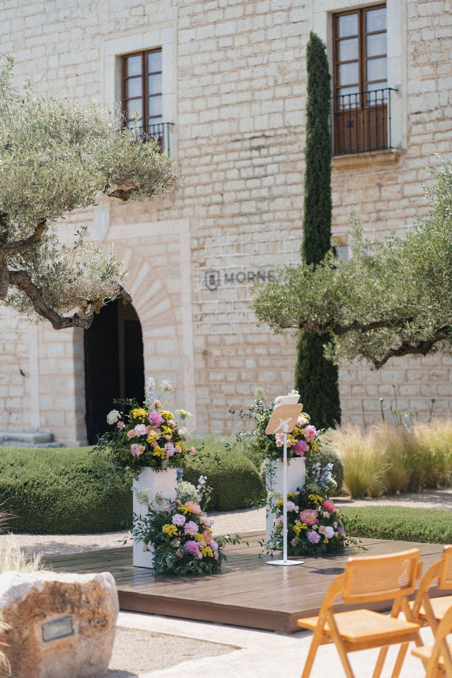 Outdoor wedding ceremony setup with colorful floral arrangements at historic stone venue El Morne.