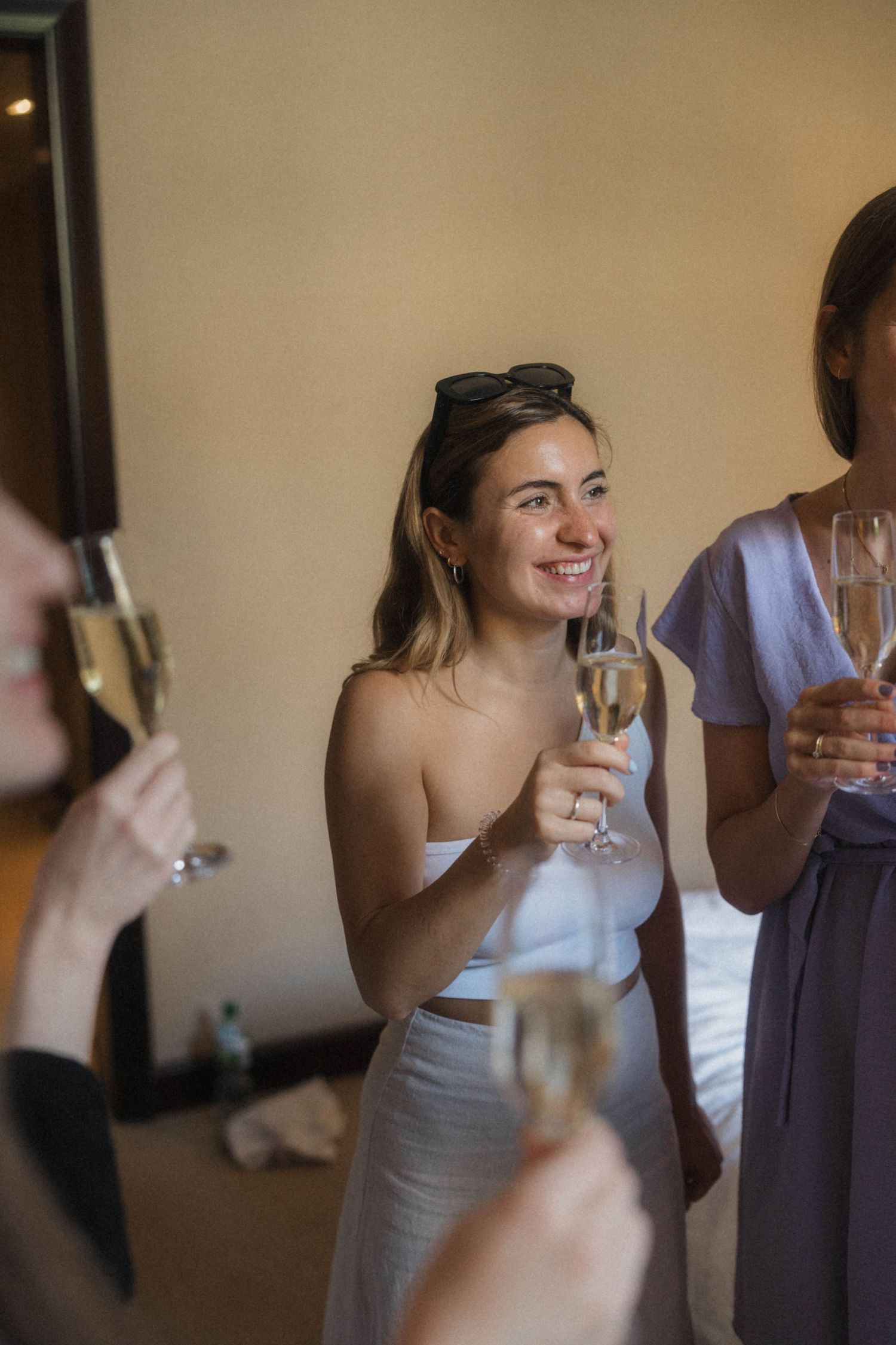 Women celebrating with champagne flutes, smiling and toasting indoors at a wedding party event.