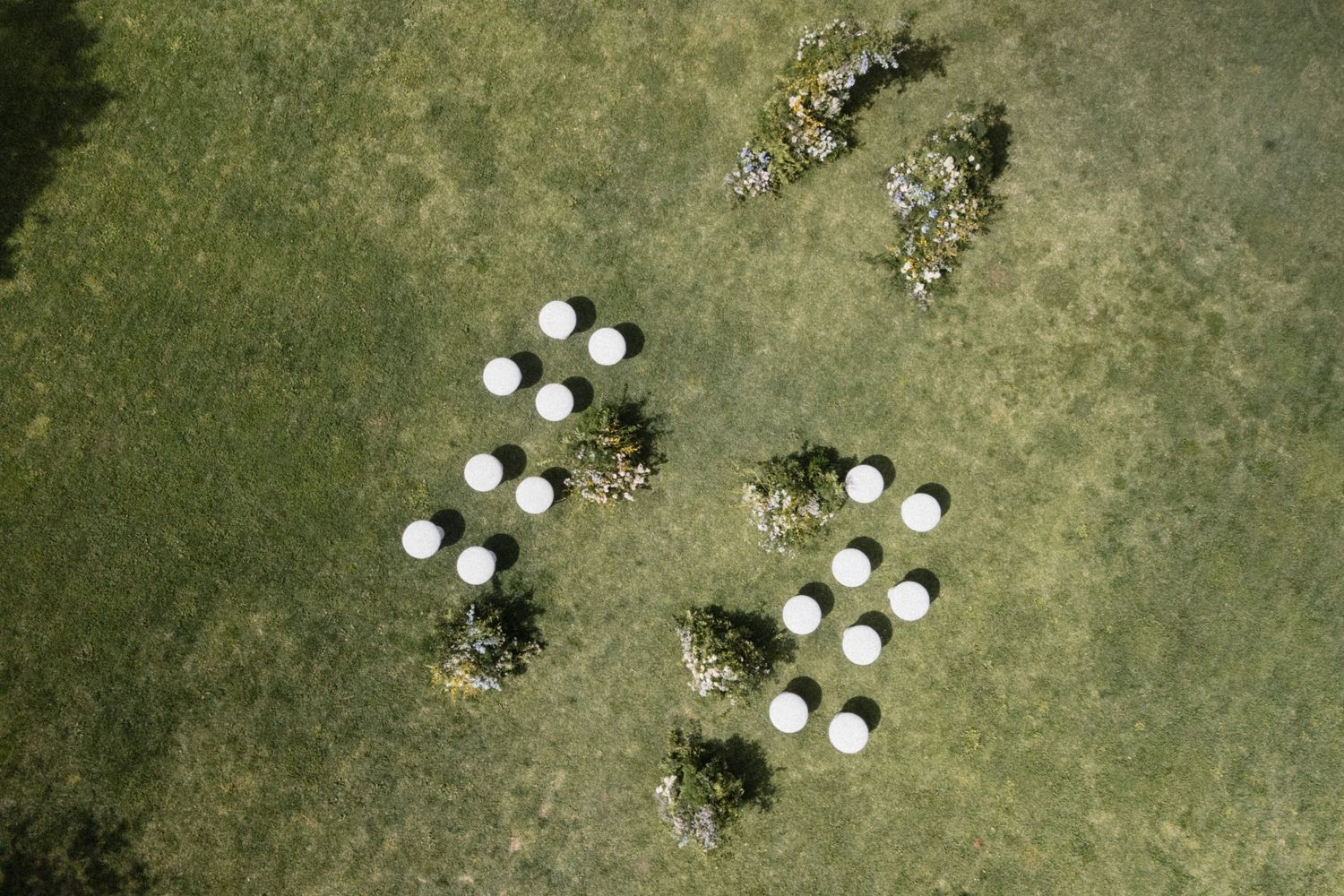 Aerial view of white circular objects arranged in cross patterns on green grass field.