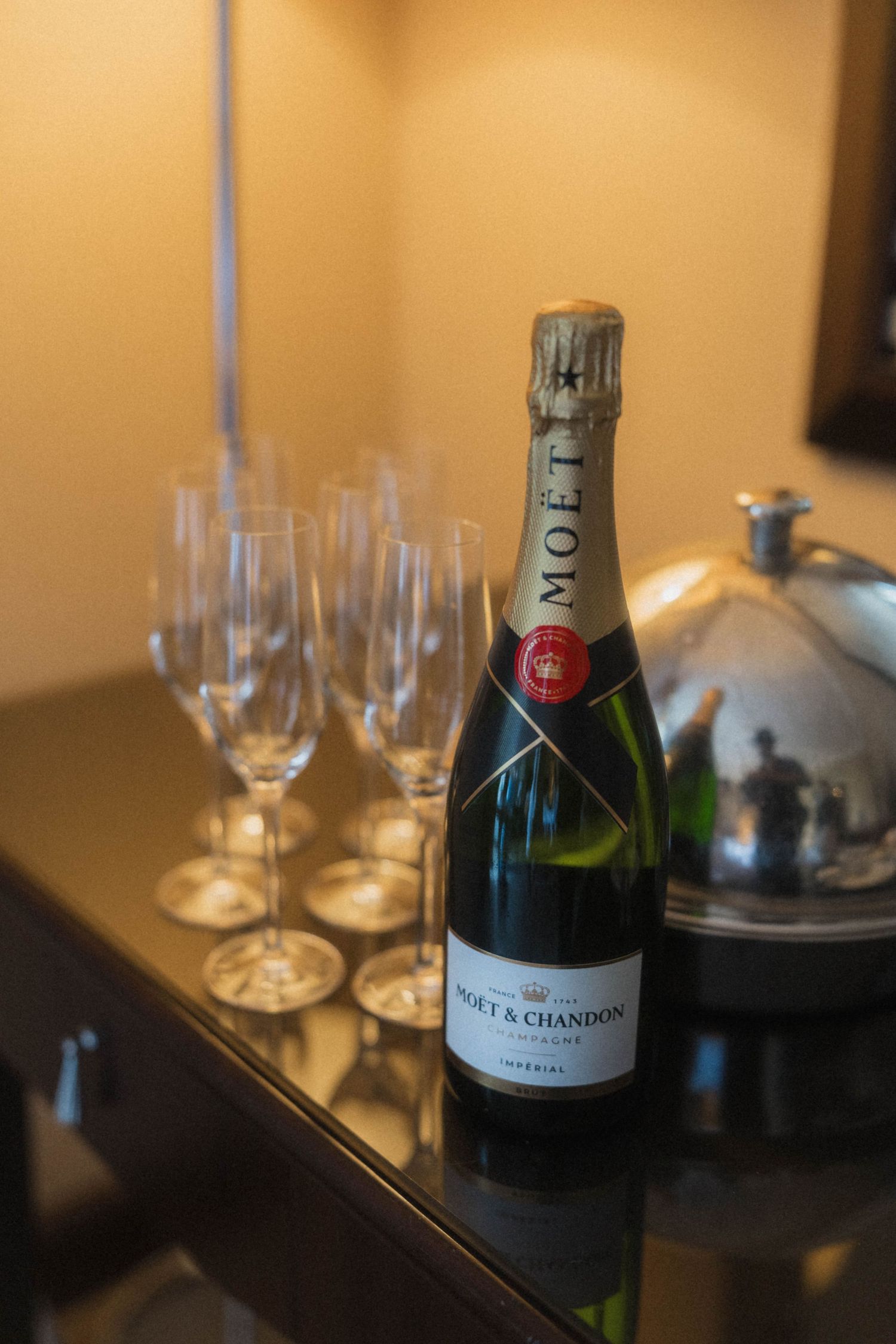 Moet & Chandon Imperial champagne bottle with elegant flute glasses on a dark surface at a wedding reception.