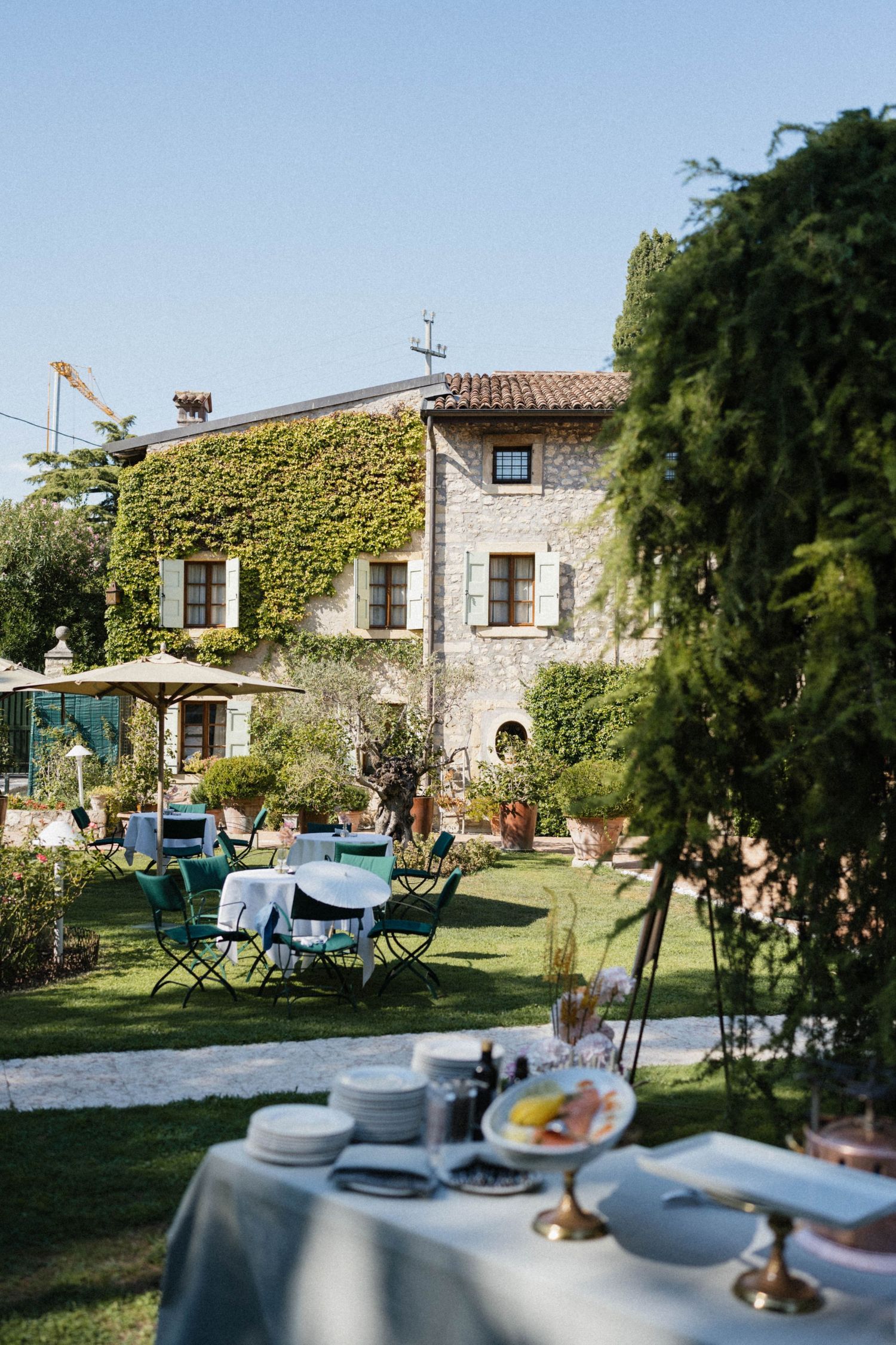 Rustic Italian villa covered in ivy with outdoor dining tables set on manicured lawn.