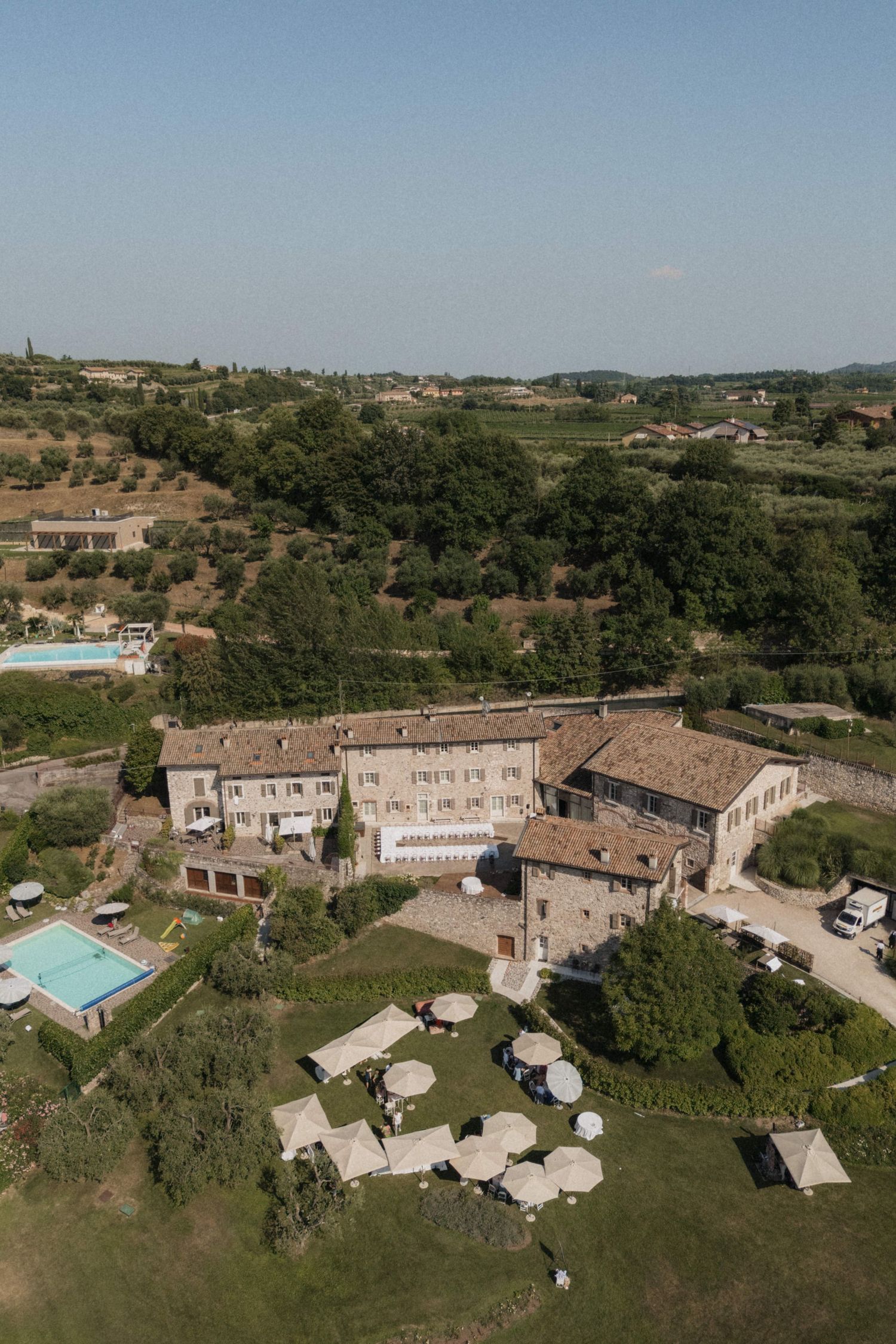 Aerial view of rustic Italian villa wedding venue surrounded by lush greenery and rolling hills.