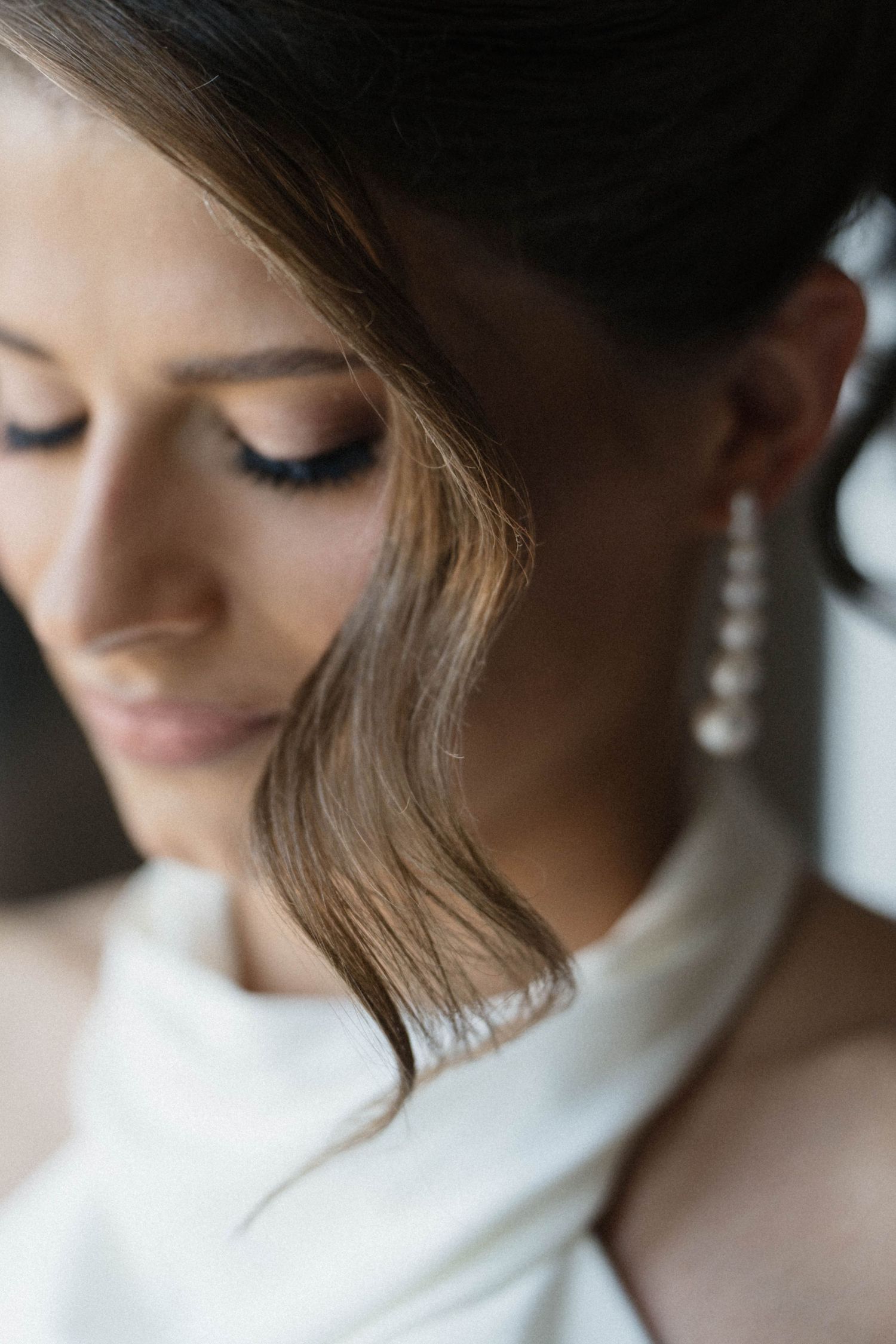 Bride wearing elegant pearl drop earrings with soft bridal makeup and updo hairstyle.