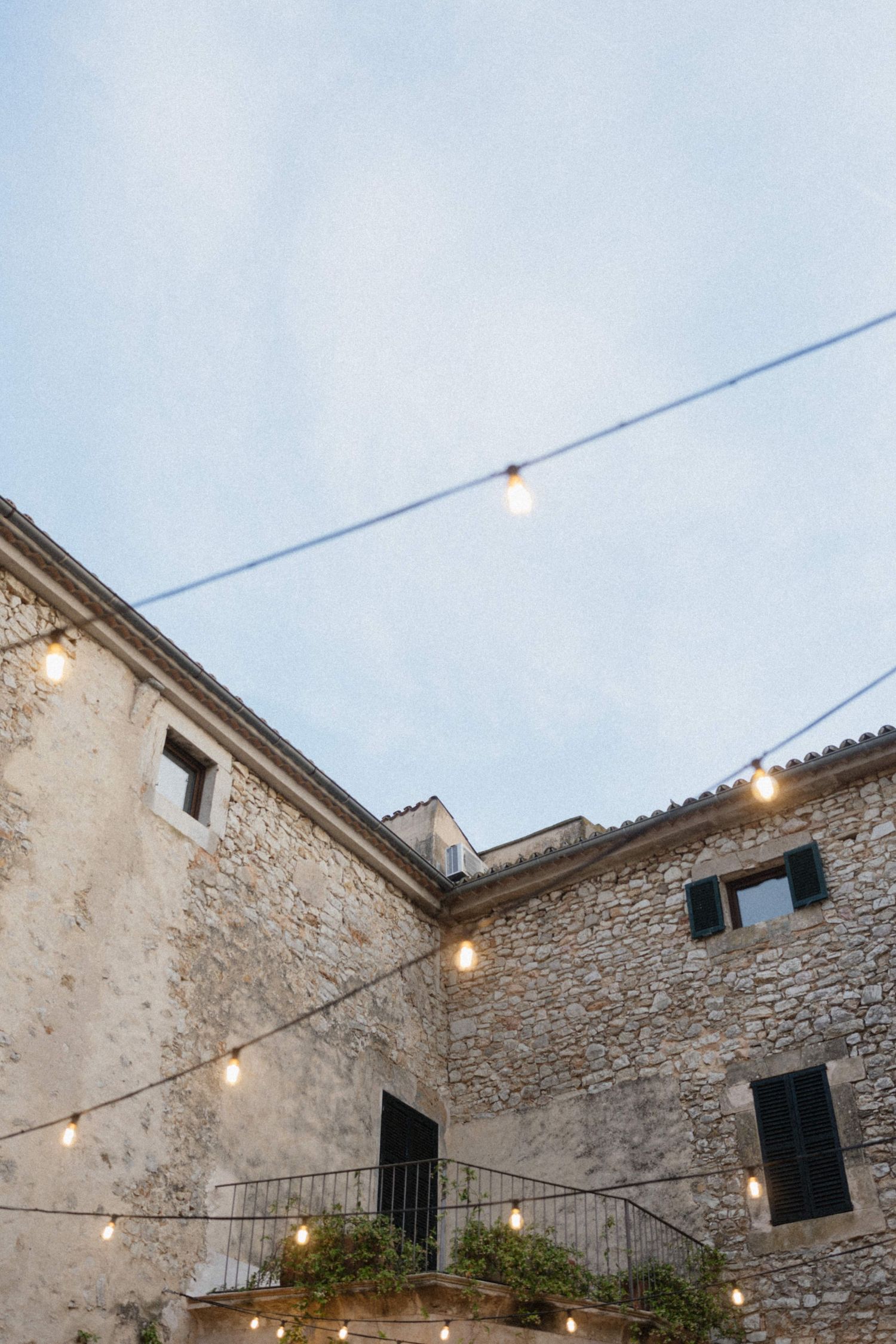 Rustic stone venue with string lights at dusk for outdoor wedding reception.