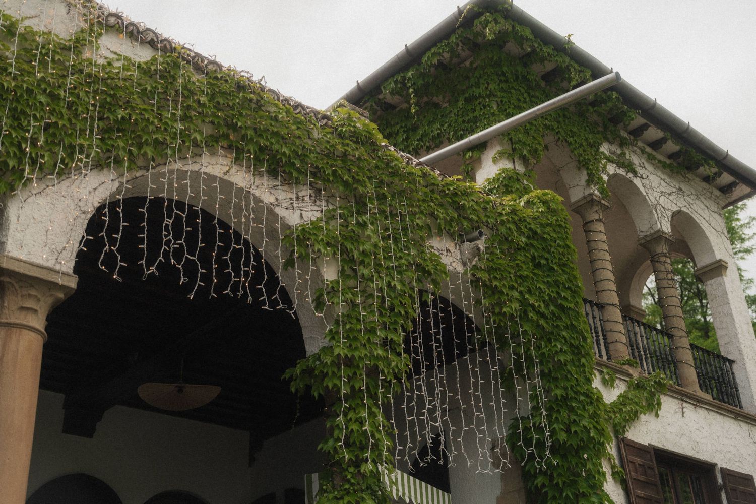 Ivy-covered stone arched venue decorated with hanging crystal wedding lights.