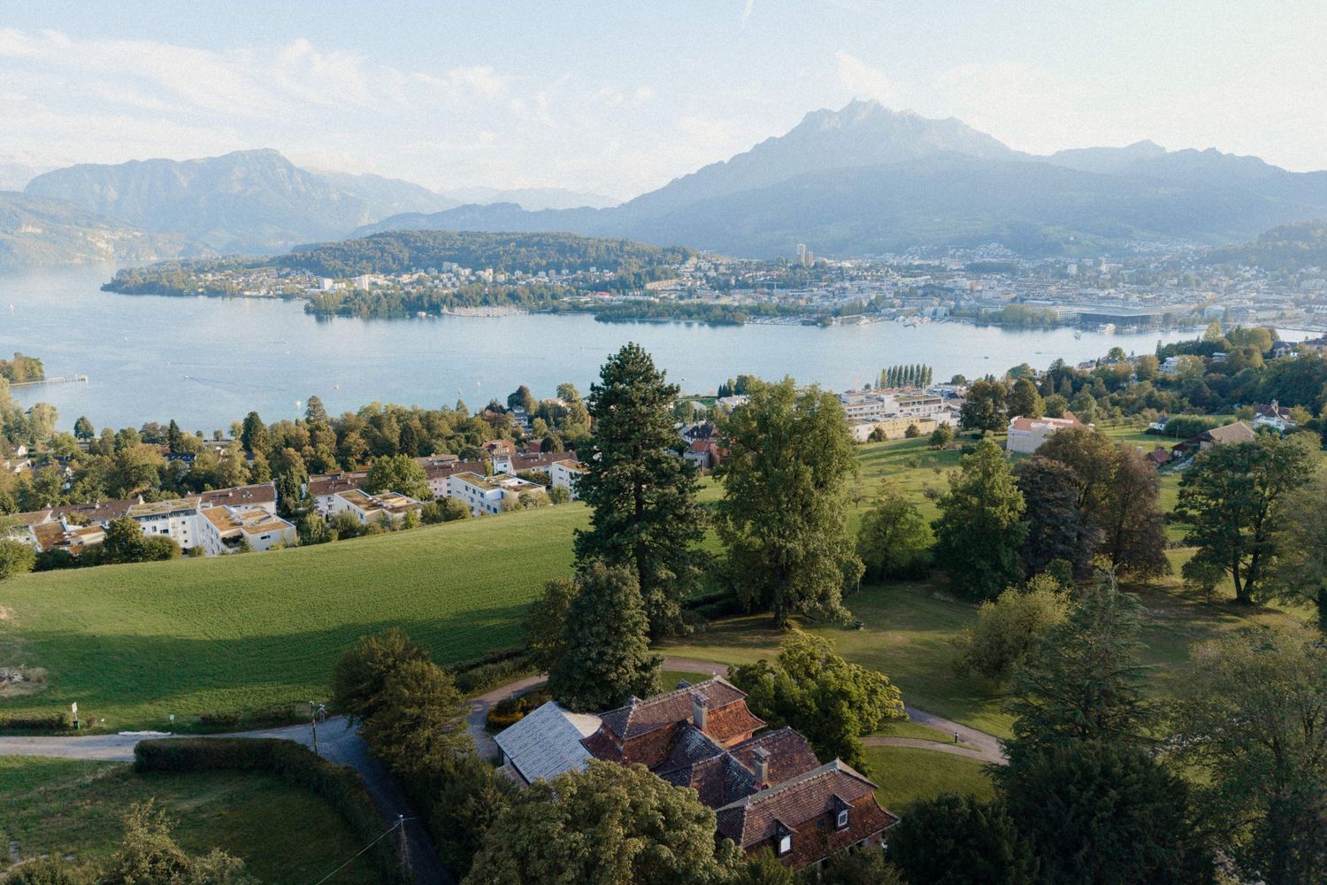 Aerial view of Swiss lakeside town with mountains and lush green landscape.