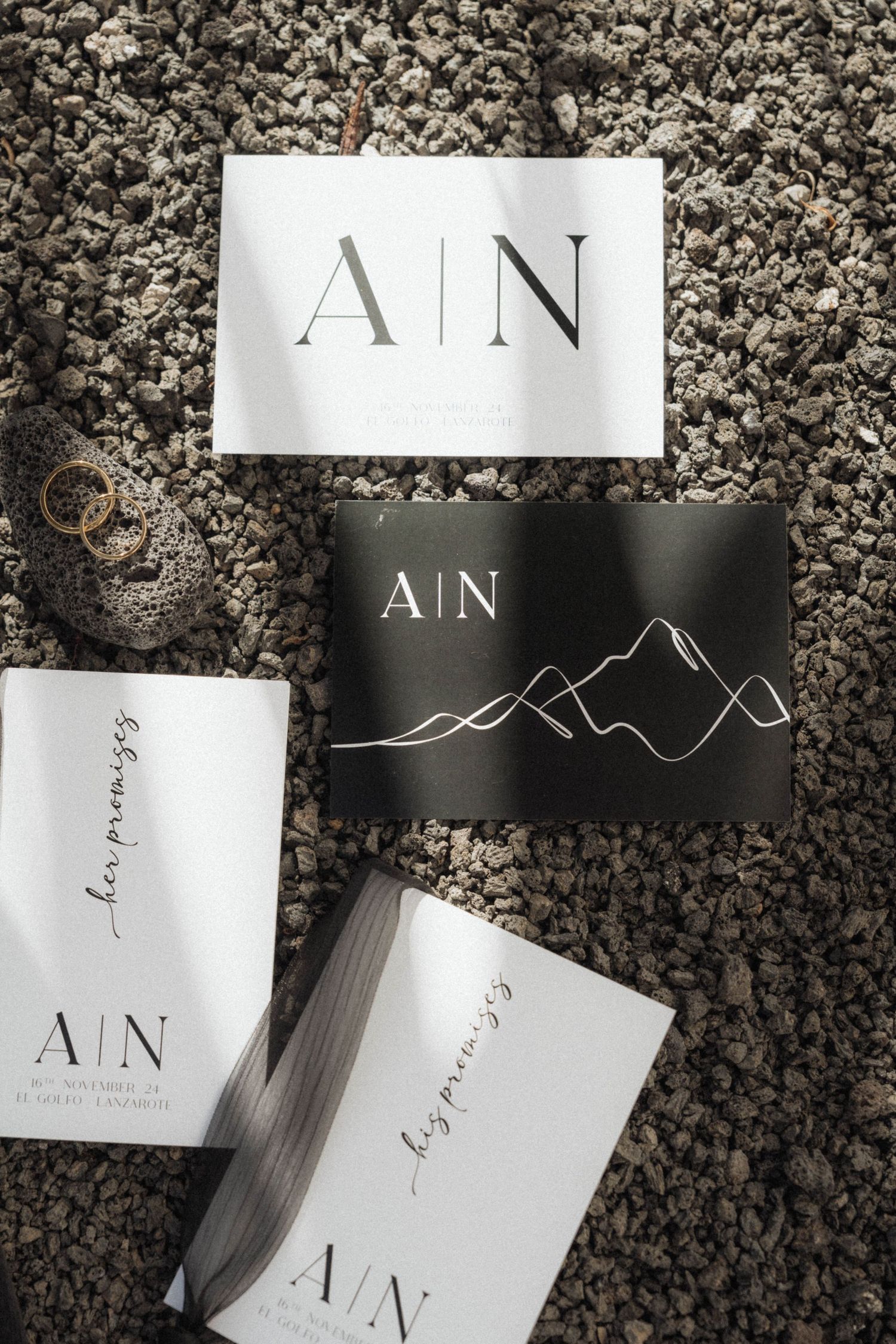 Elegant black and white wedding stationery suite with A|N monogram and mountain motif on volcanic rock.