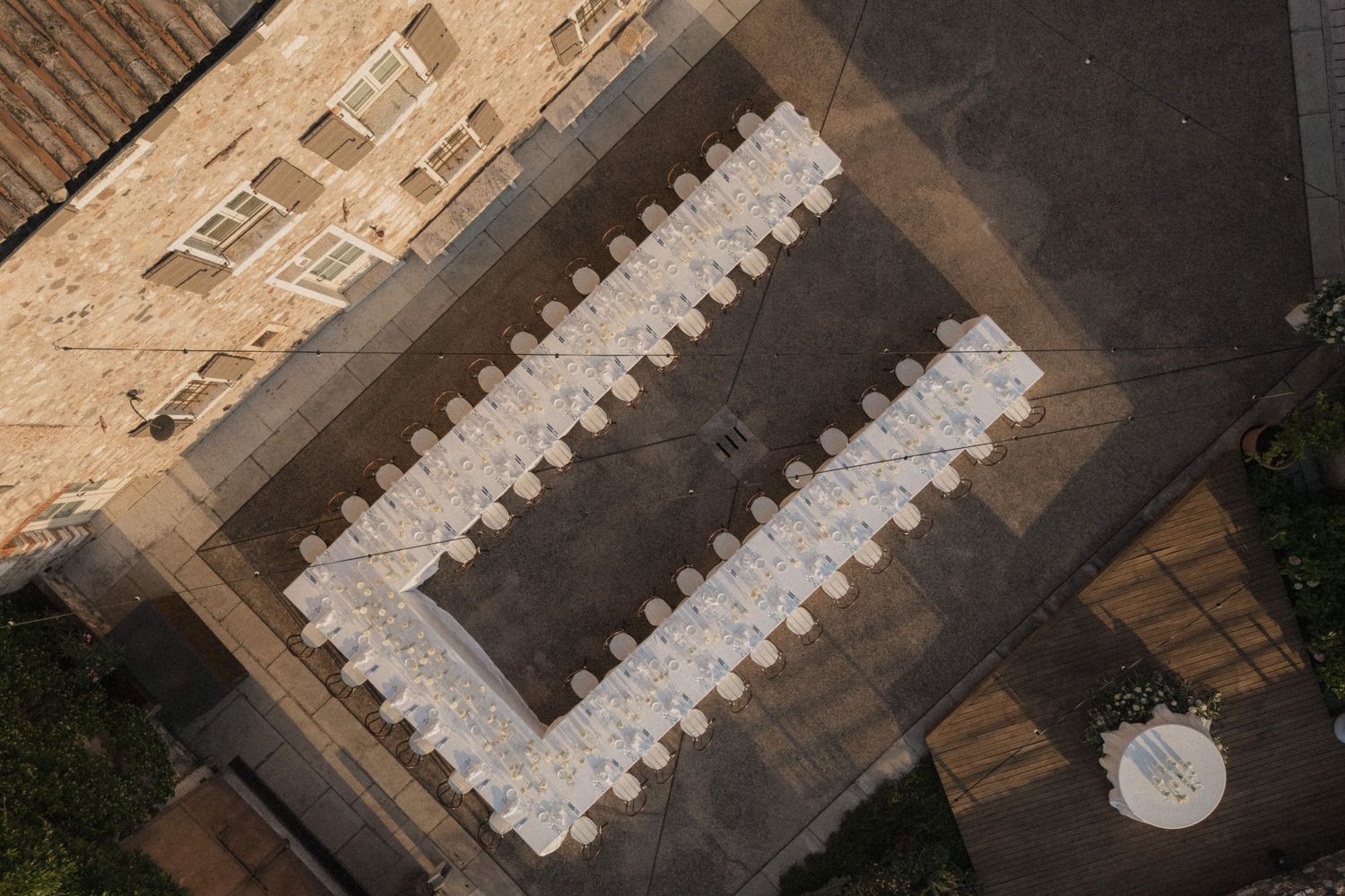 Bird's eye view of U-shaped wedding reception table arrangement in stone courtyard.
