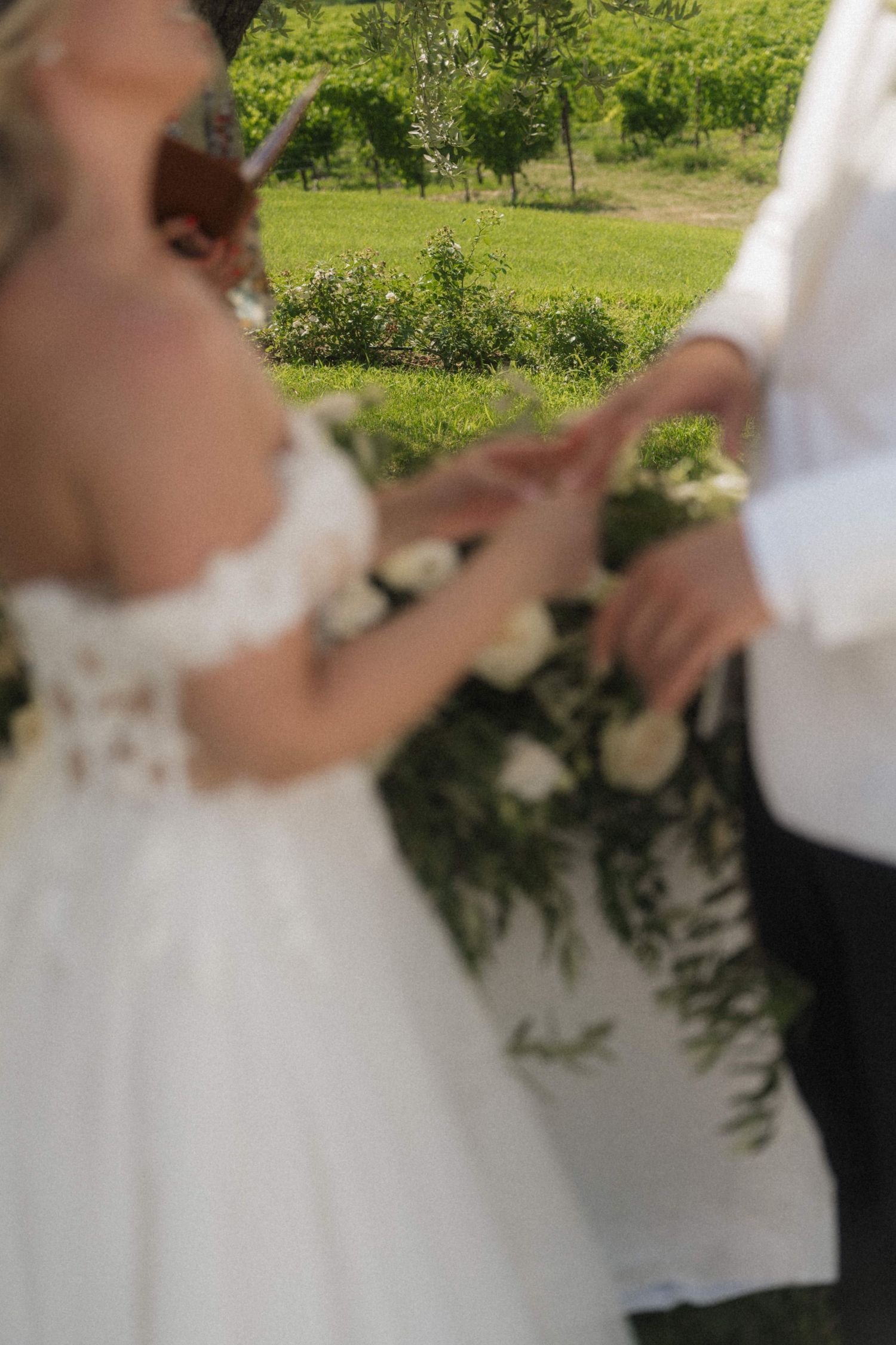 Bride and groom exchanging rings during outdoor wedding ceremony surrounded by white floral decor.
