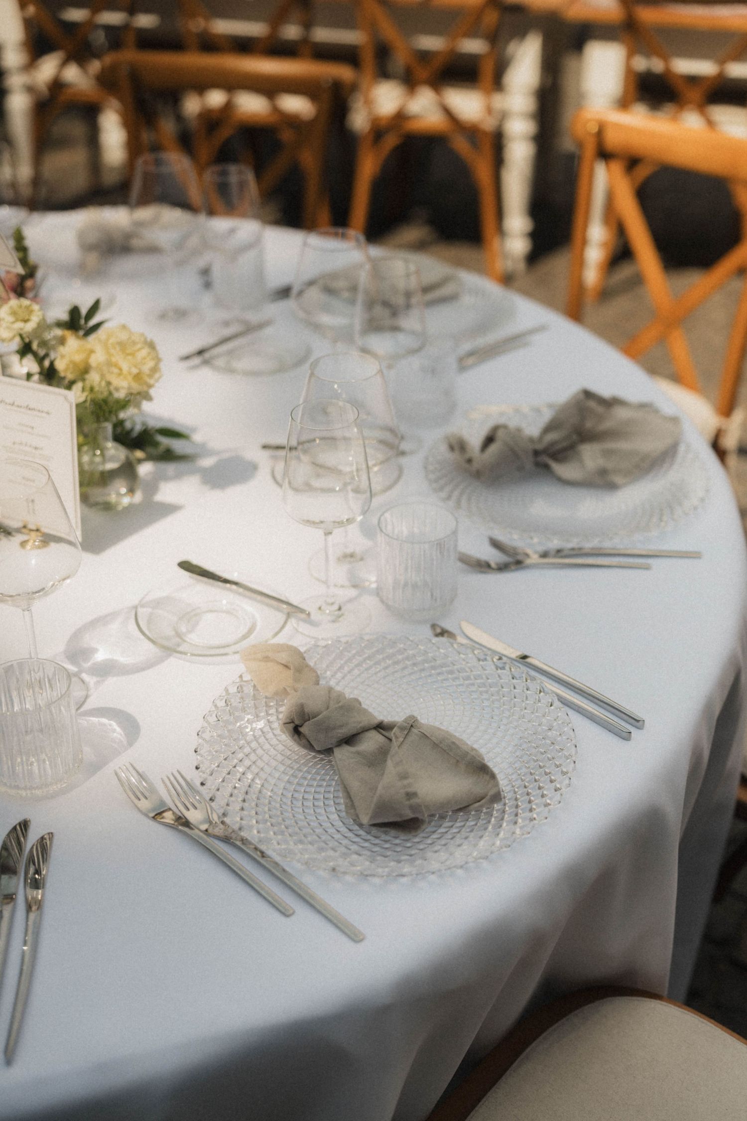 Elegant white wedding reception table setting with crystal glassware and linen napkins.