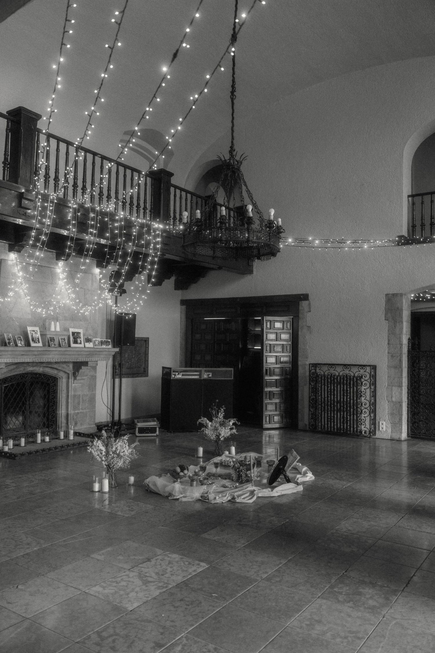 Black and white photo of fairy light decorated wedding reception hall interior.