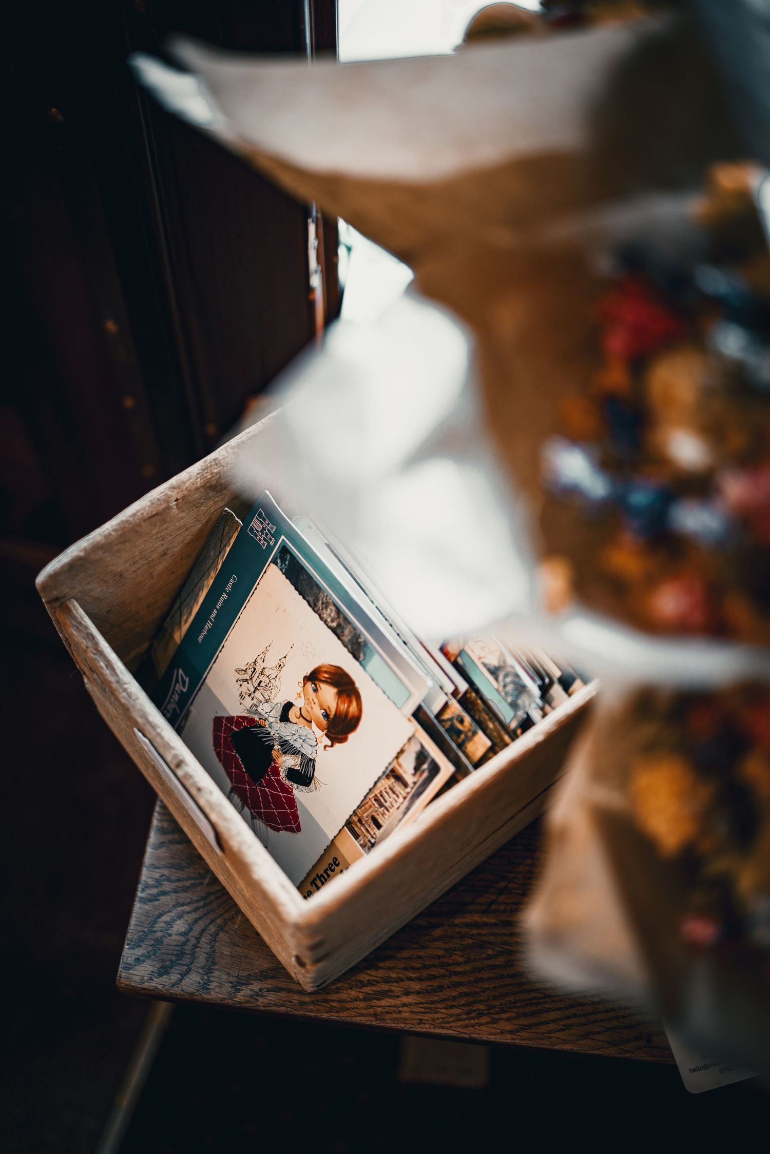 Vintage postcards and photographs stored in a rustic wooden box on a antique wooden table in dim light.