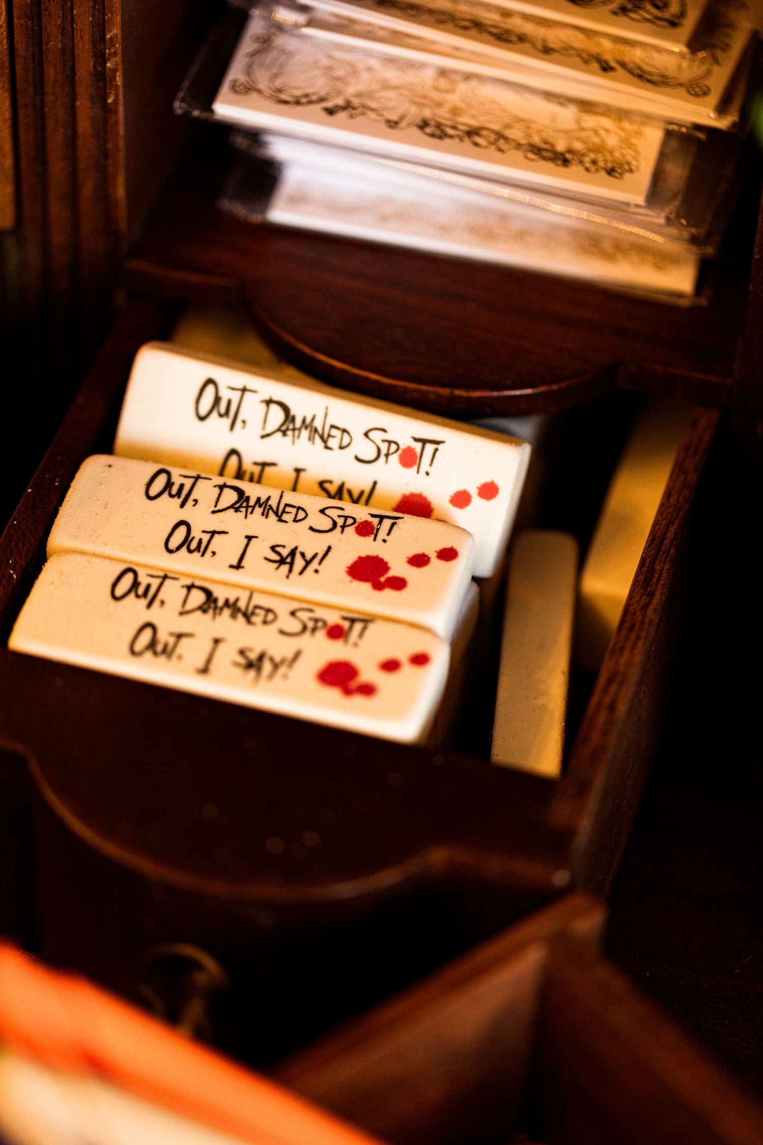 Wooden box with soap bars reading 'Out, Damned Spot! Out, I say!' with red blood drop designs, inspired by Macbeth.