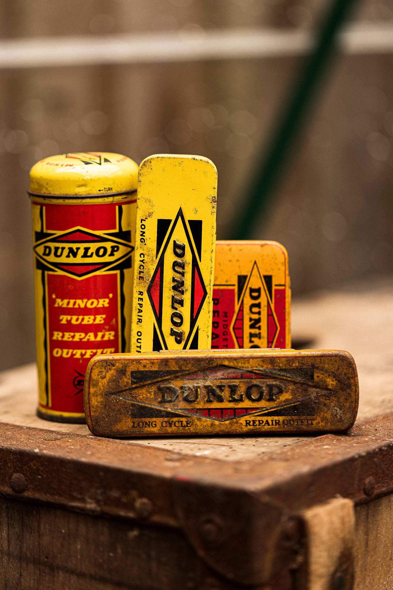Vintage Dunlop minor tube repair outfit tins in yellow and red displayed on a wooden surface.