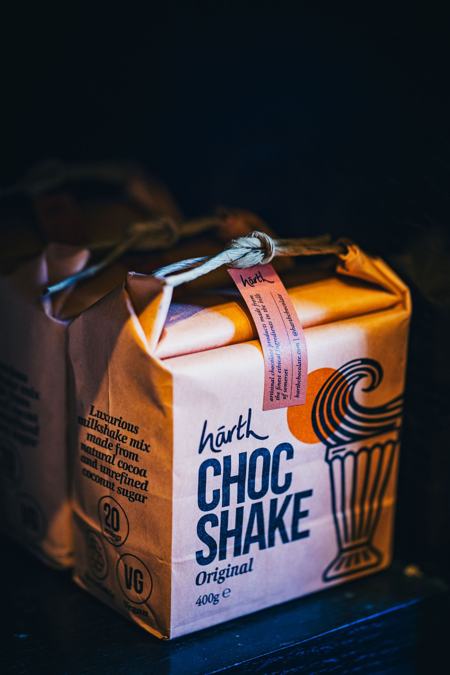 Hartk Choc Shake original 400g product packaging on a dark background with warm lighting.