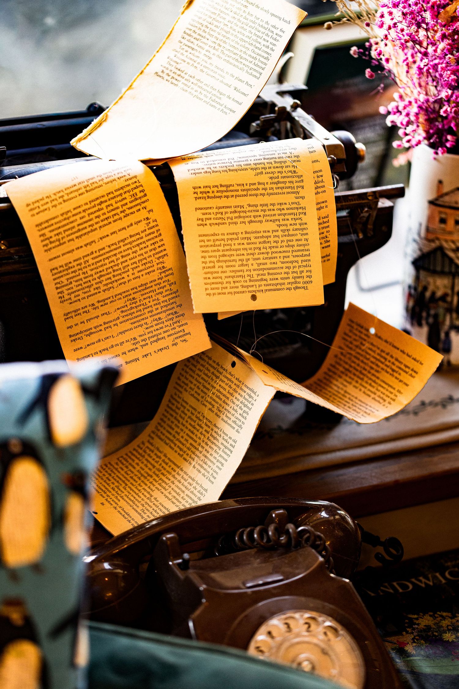 Pages of text flowing from a vintage typewriter with an antique rotary telephone nearby.
