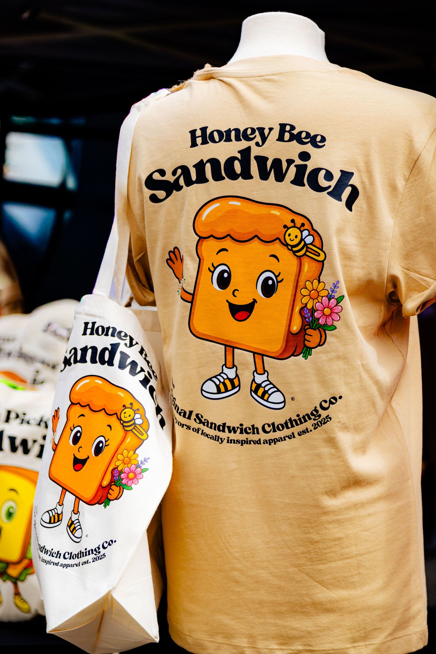 Beige t-shirt featuring a Honey Bee Sandwich cartoon character with floral design.