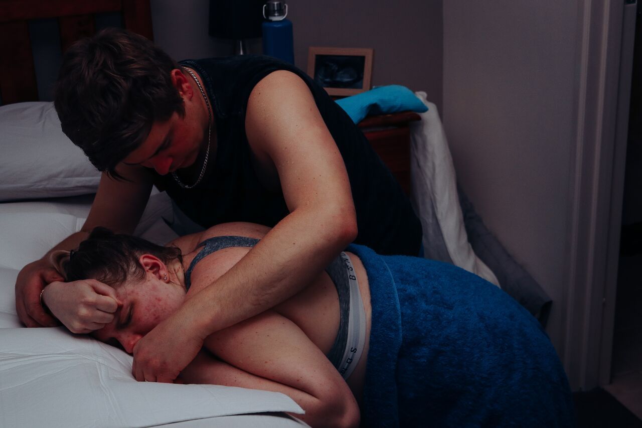 Two people in an intimate embrace on a bed in a dimly lit bedroom at night.