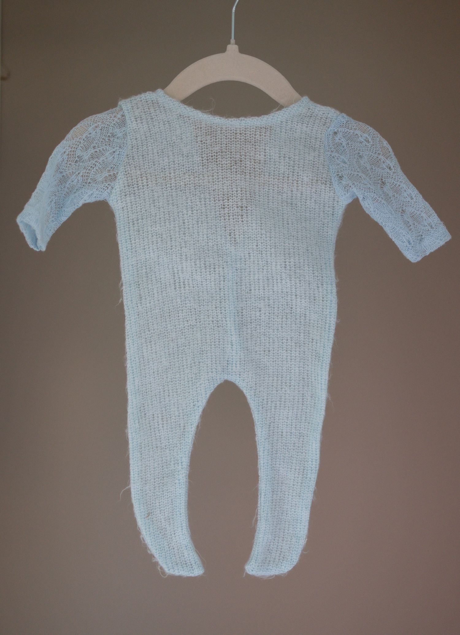Light blue knitted baby footed romper with lace puff sleeves displayed on a hanger. Taken by Golden Hour Perth