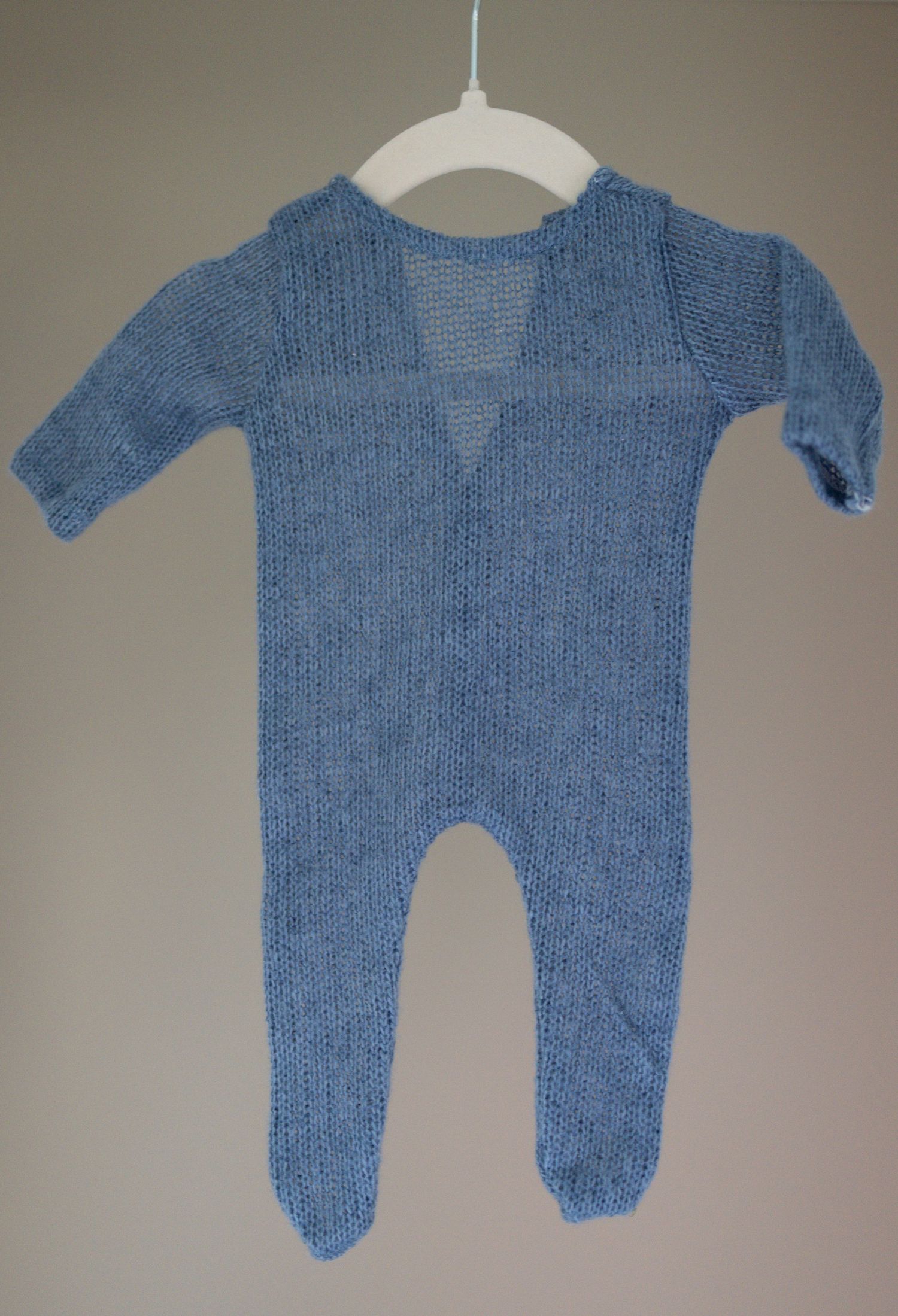 Hand-knitted blue baby romper with long sleeves and footed legs displayed on a white hanger. Taken by Golden Hour Perth