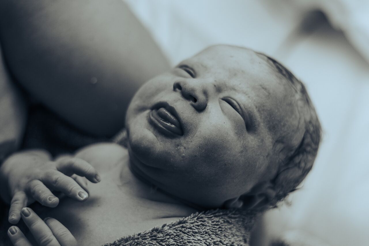 Black and white close-up of a crying newborn baby just moments after birth.