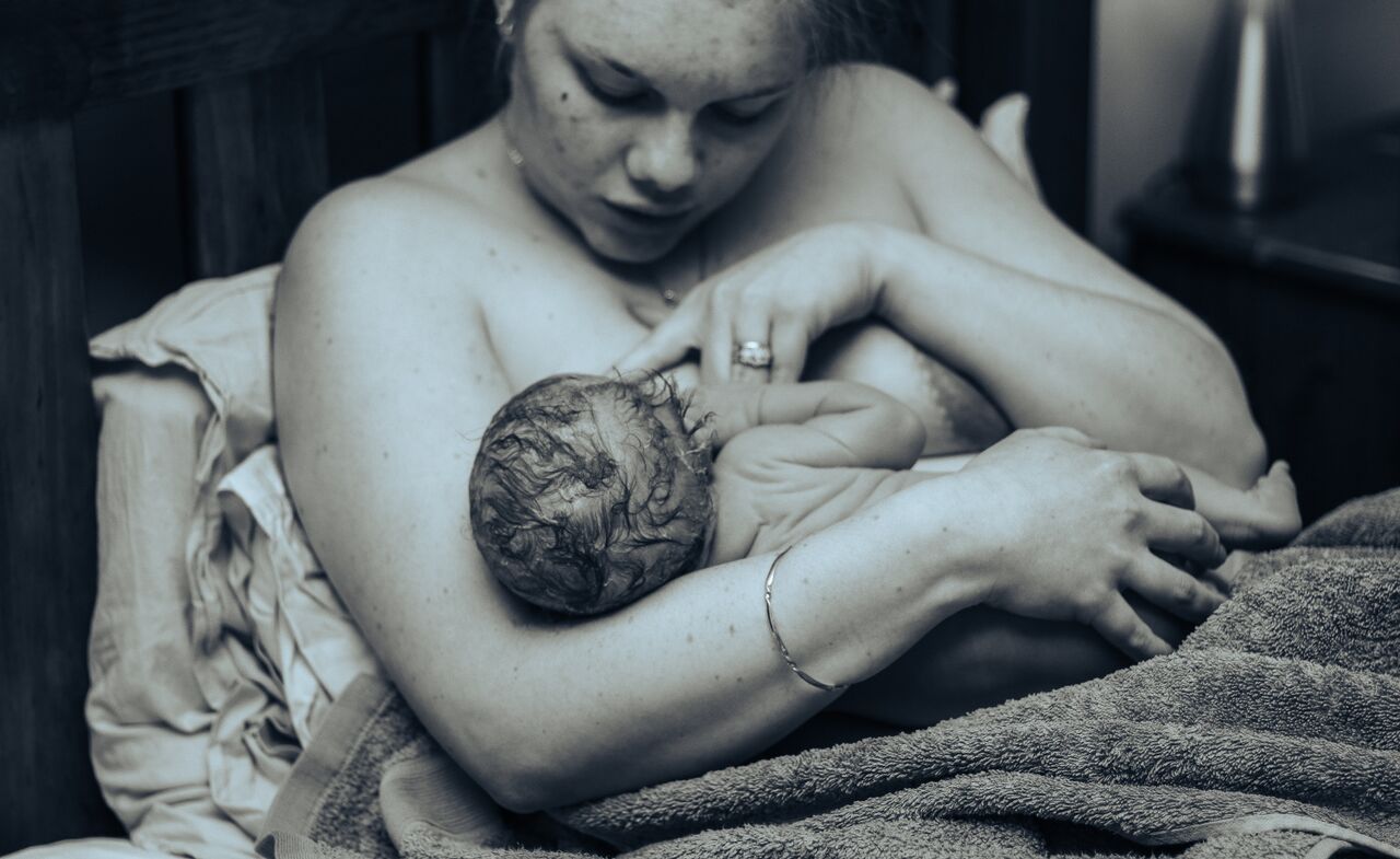 Black and white photo of a mother holding her newborn baby skin-to-skin after childbirth.