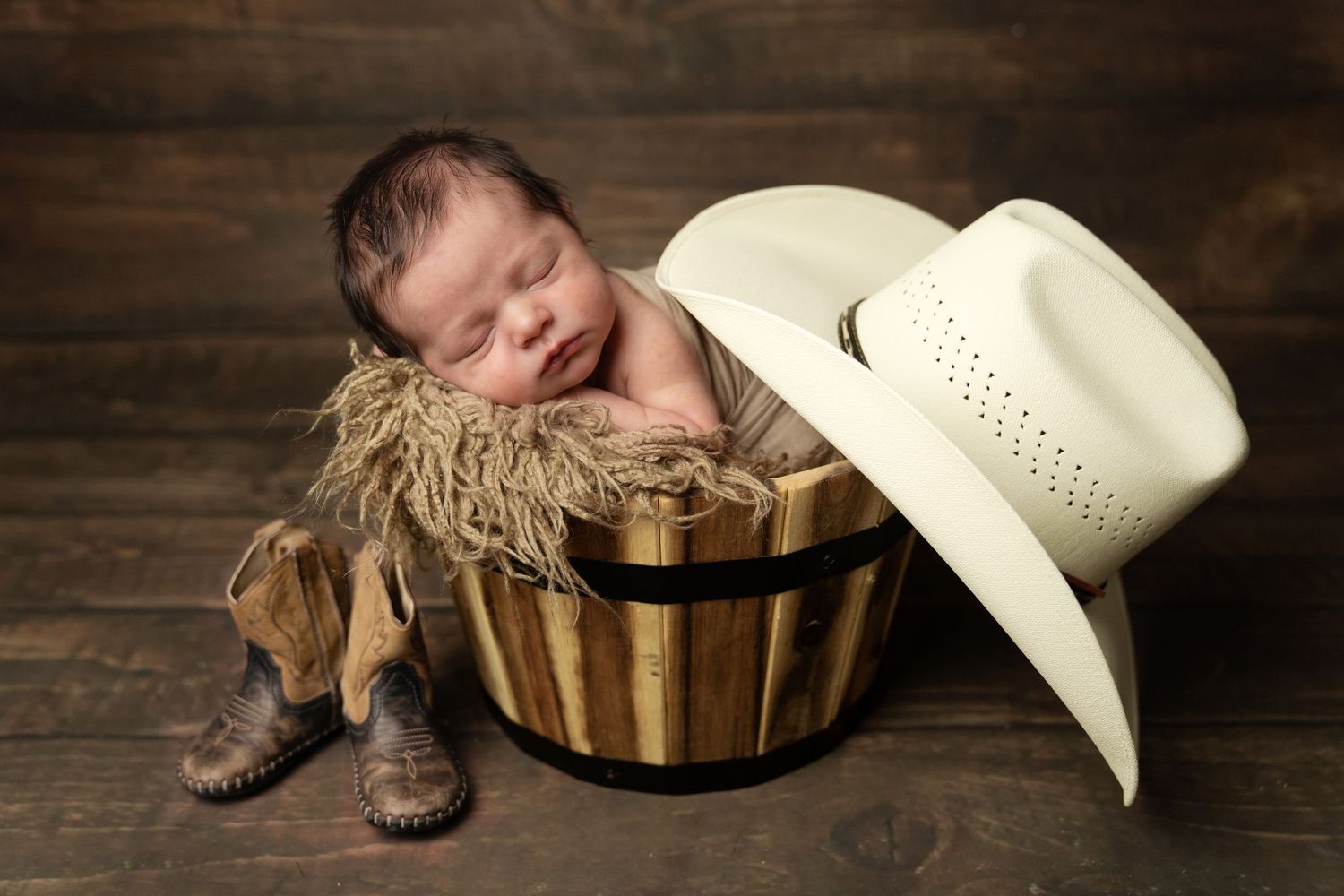 sleeping newborn in cowboy theme bucket. Captured in Woodland Hills by the most sought-after professional maternity and newborn photographer