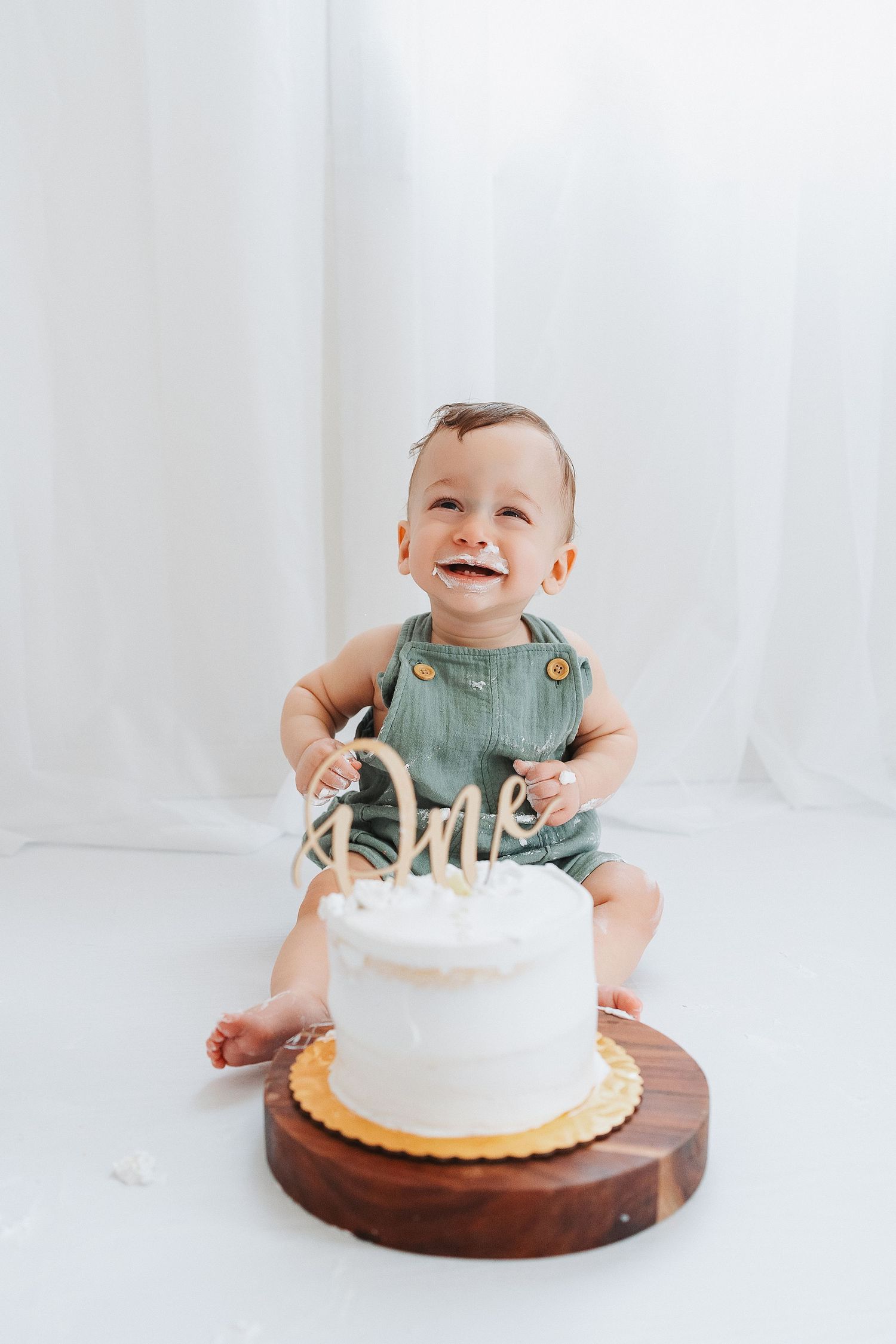 Smiling baby eating cake in our Woodland Hills studio. Amazing milestone photography in Los Angeles & the SF Valley.