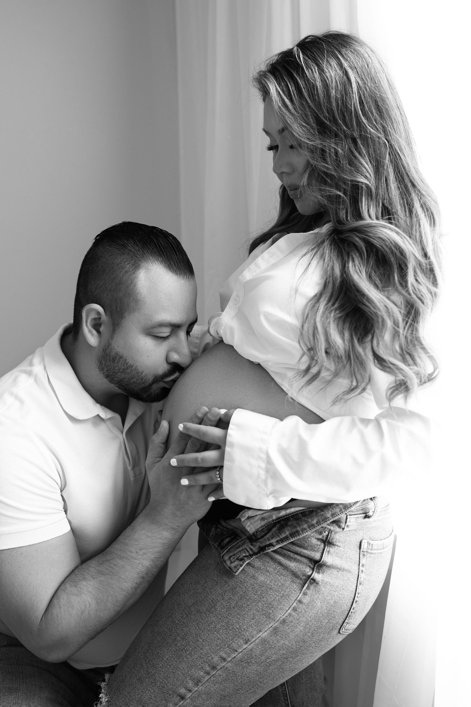 Pregnant mom and partner kissing belly, at our Woodland Hills studio. The best maternity photographer in Los Angeles.