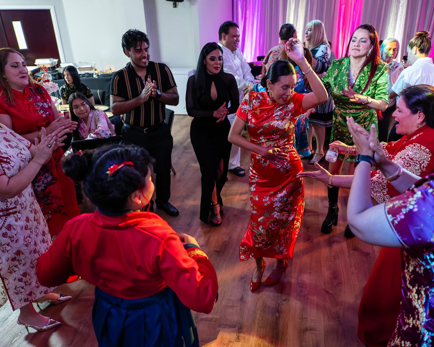 Guests in colorful traditional attire dance joyfully at a festive cultural celebration event.