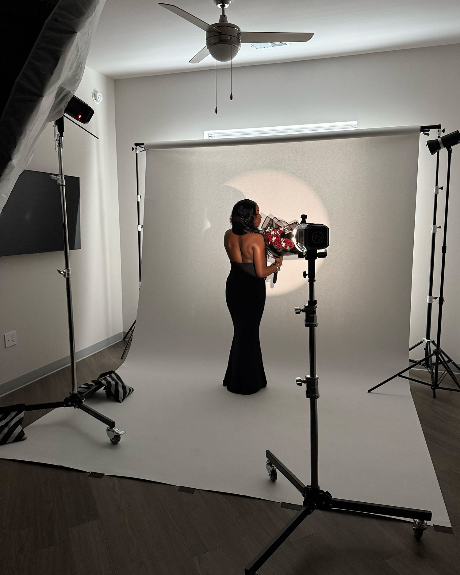Behind-the-scenes view of a professional photo studio shoot with lighting equipment and white backdrop.