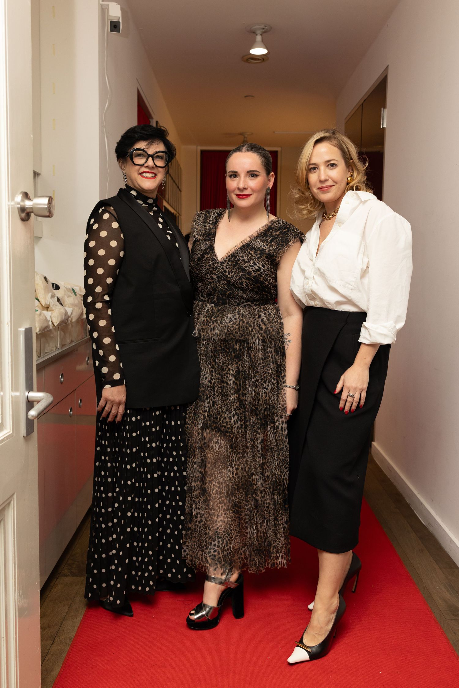 Guests posing together on the red carpet at a Flying Solo fashion event in New York City.