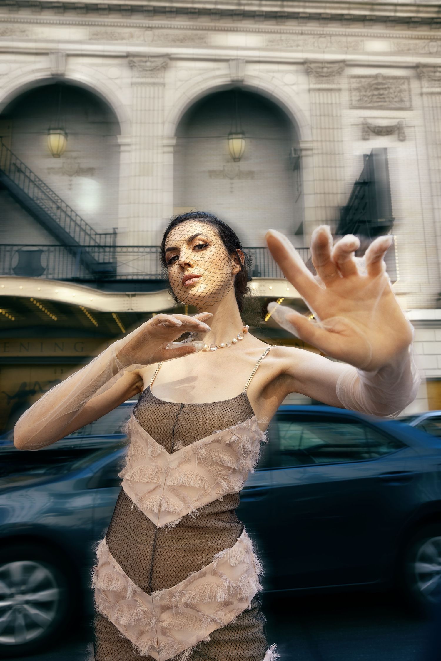 Fashion model posing on a New York City street wearing a beige dress for an editorial photoshoot.