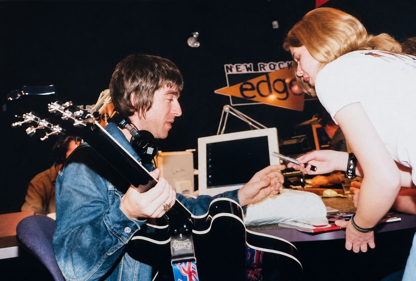 Noel Gallagher signing Lisa Mark's Union Jack Epiphone Supernova guitar in 2000 at Edge 102.1 in Toronto, ON Canada.