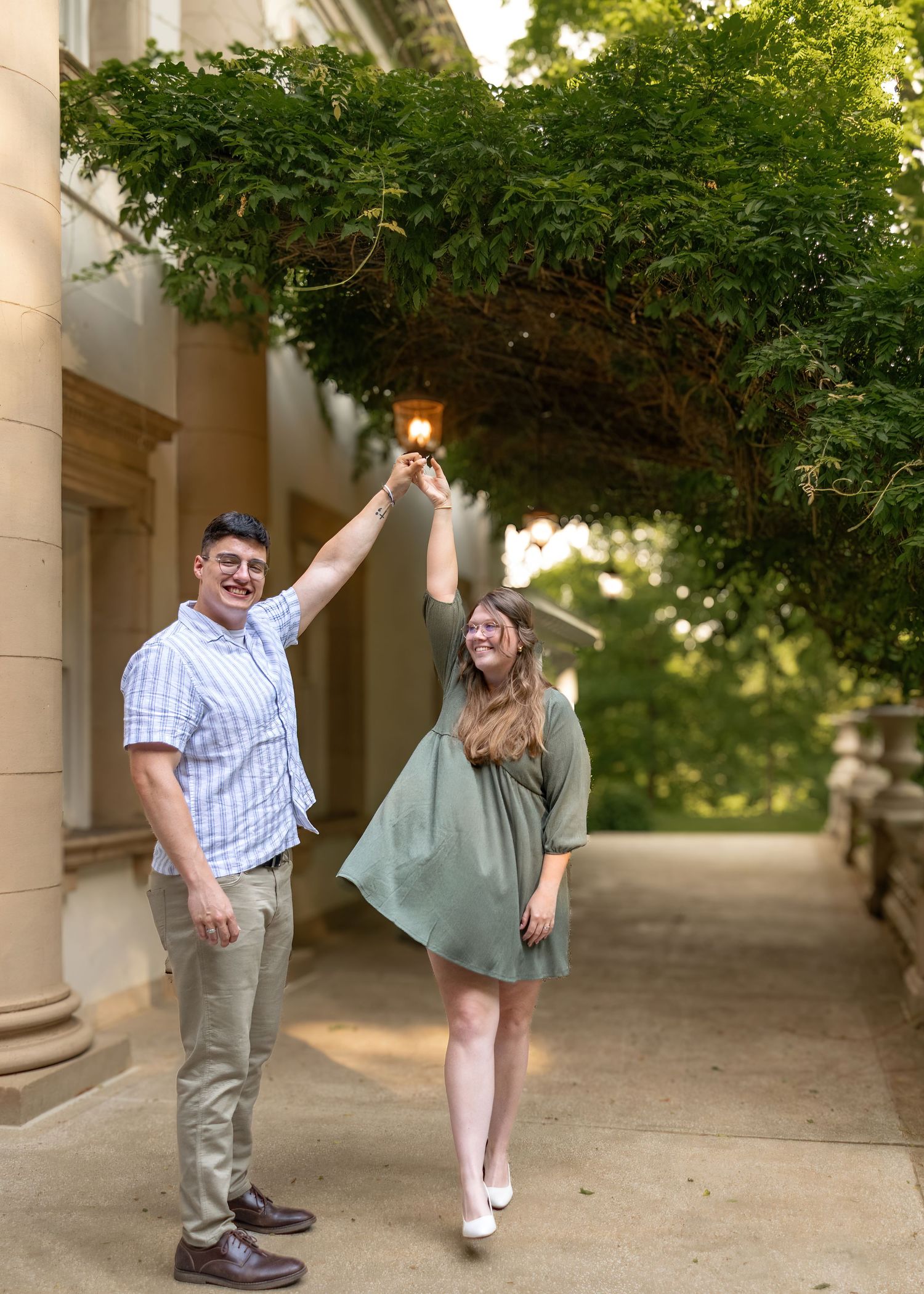 Happy couple dancing under green vine archway at elegant outdoor garden venue.