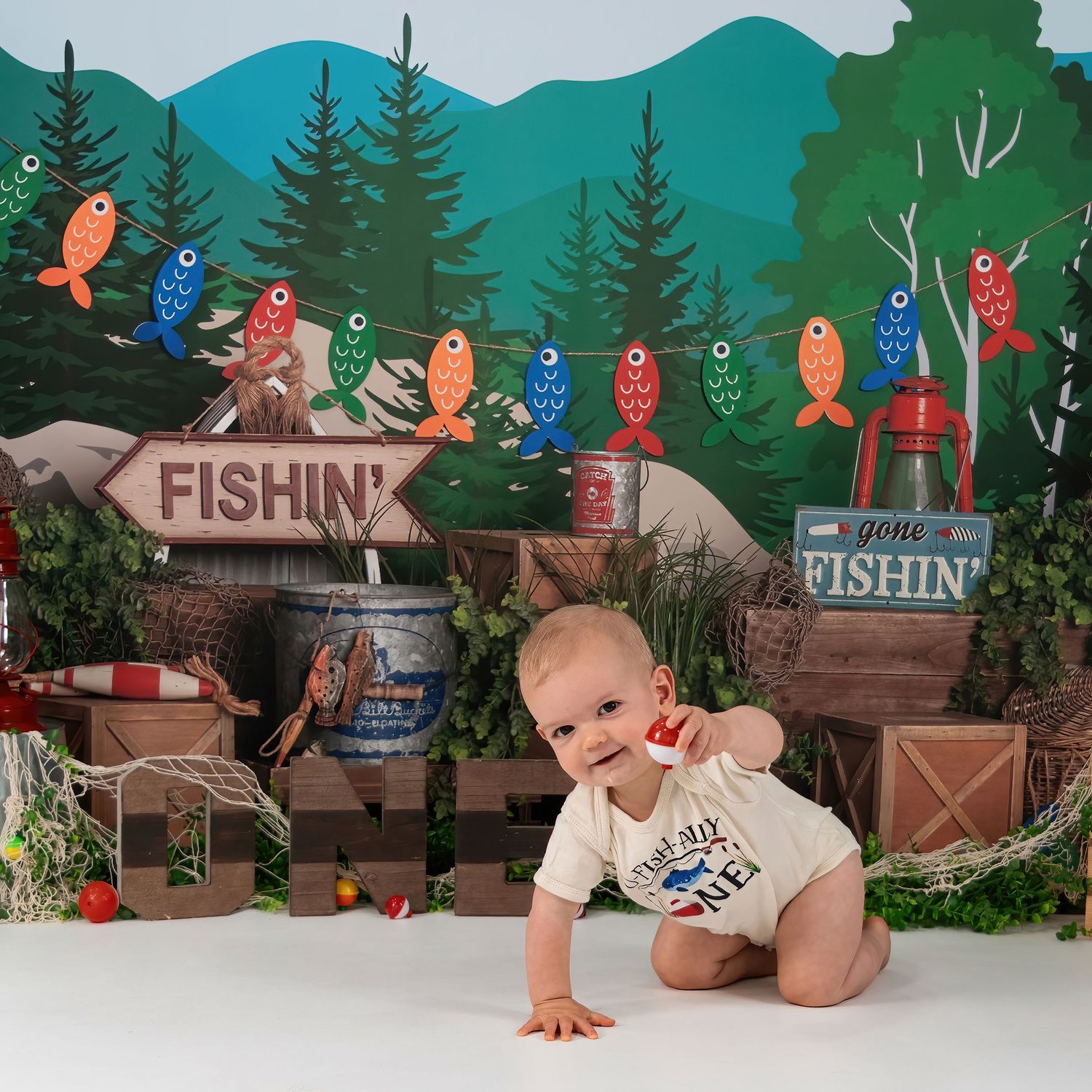 Baby boy in white onesie crawls at vibrant Gone Fishin themed first birthday cake smash session.