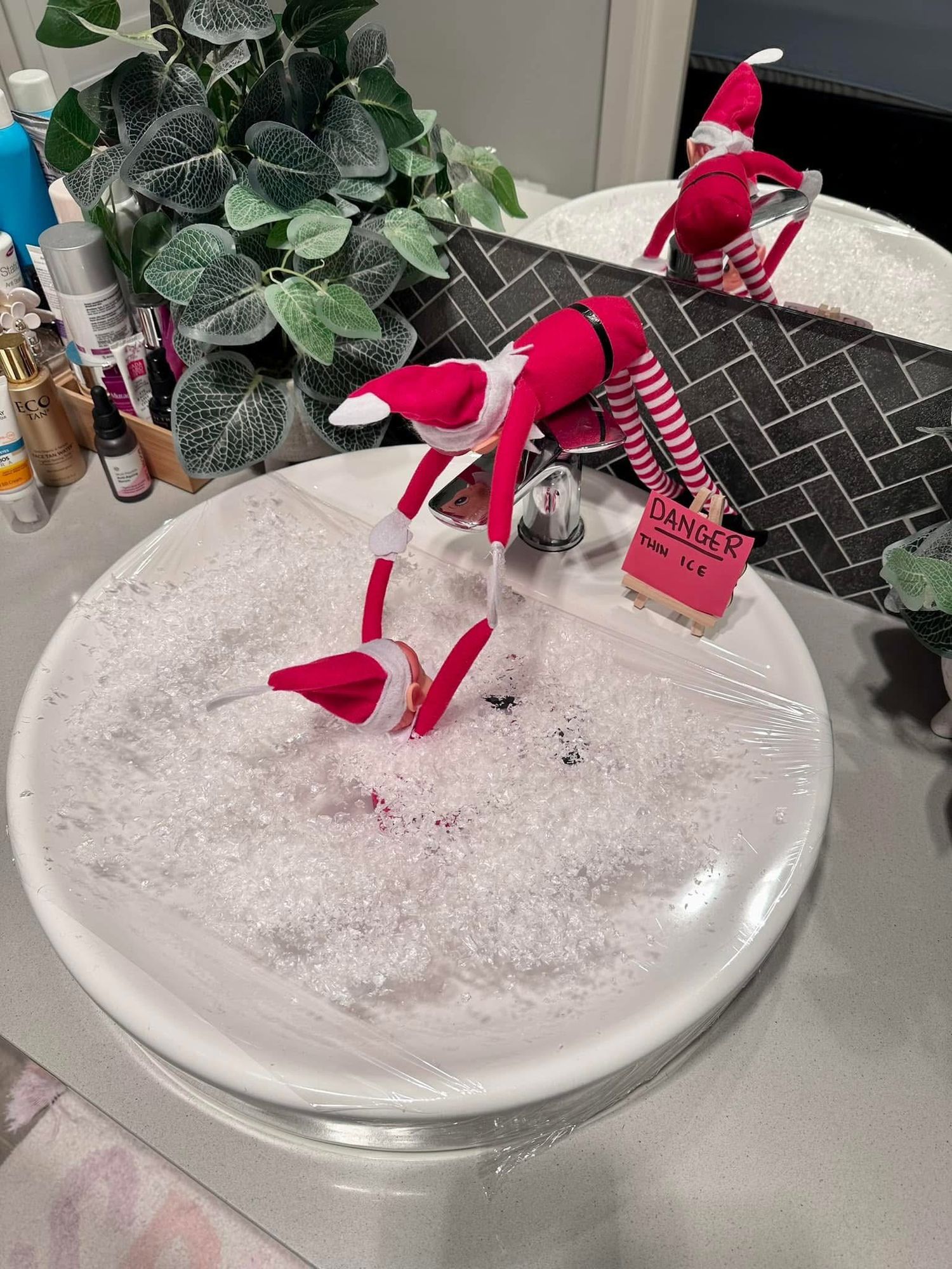 A bright pink high-heeled shoe ornament sits atop a white snowy surface in a decorative holiday display.