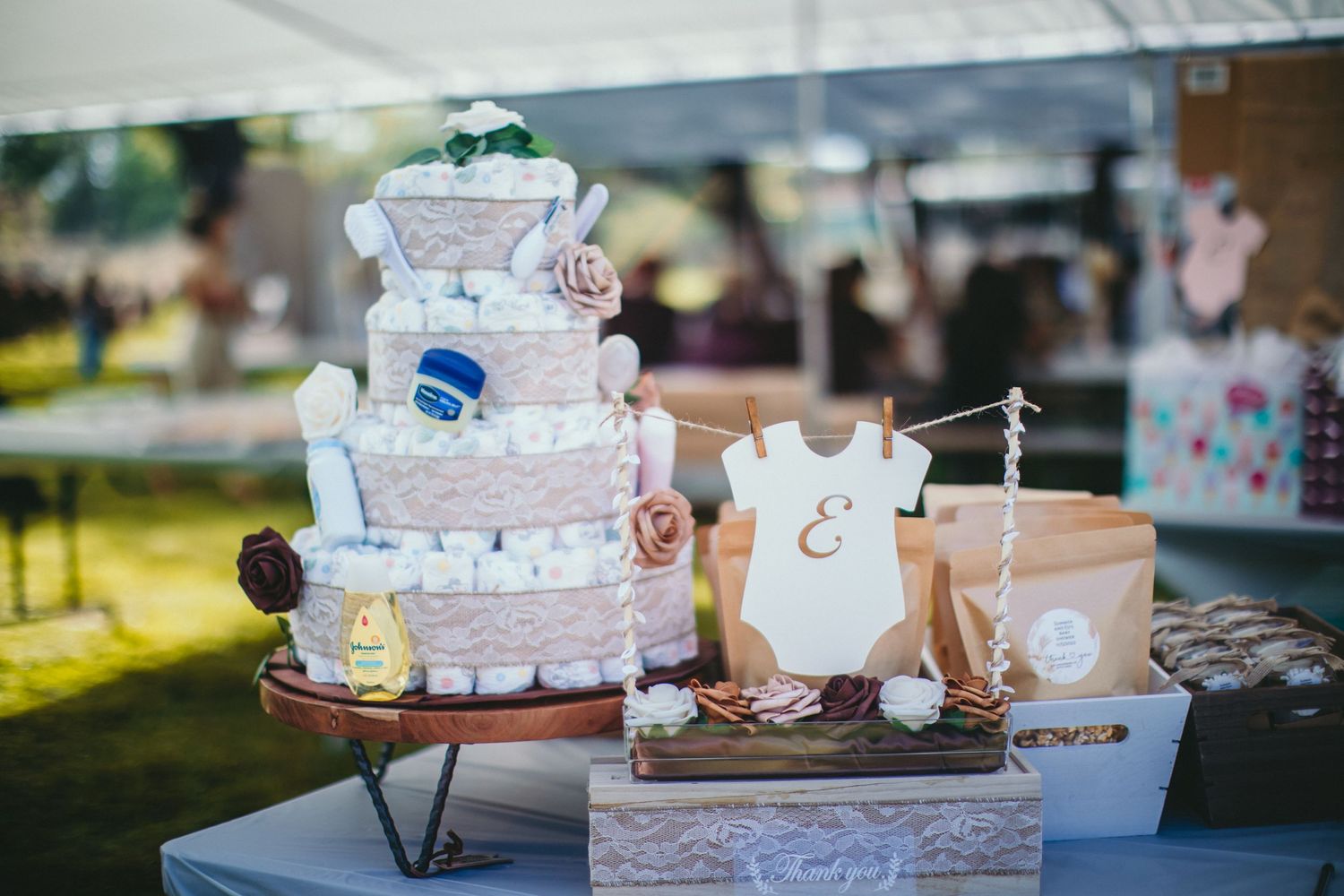 A decorative diaper cake centerpiece with baby clothes and accessories displayed at a shower.