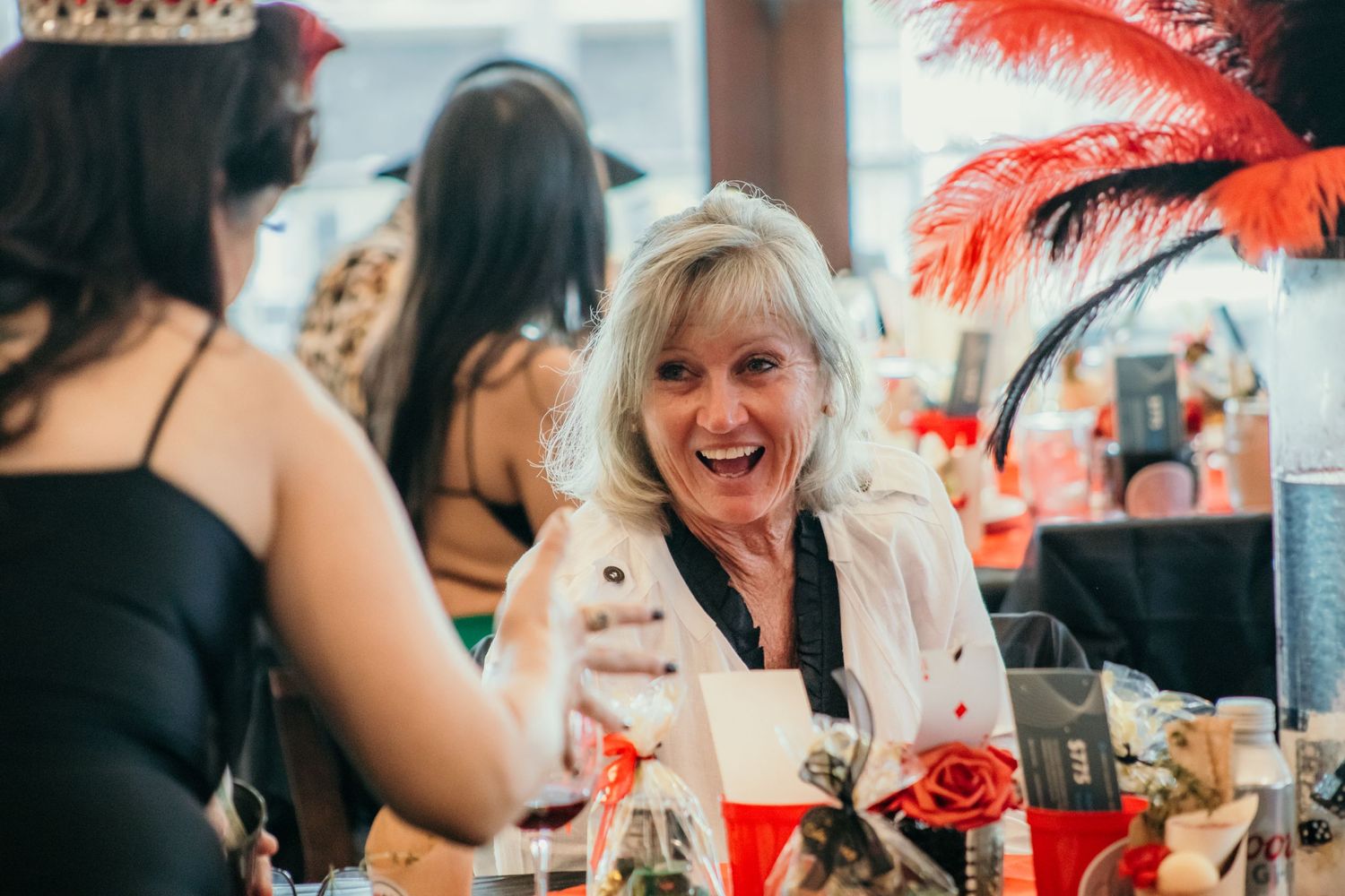 Party guests sharing laughter and drinks at a festive outdoor gathering.