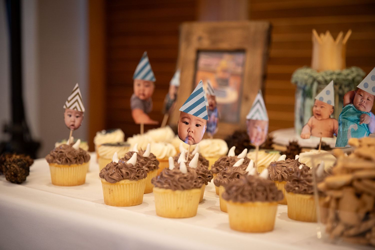Chocolate frosted cupcakes with decorative party flags displayed on a dessert table.