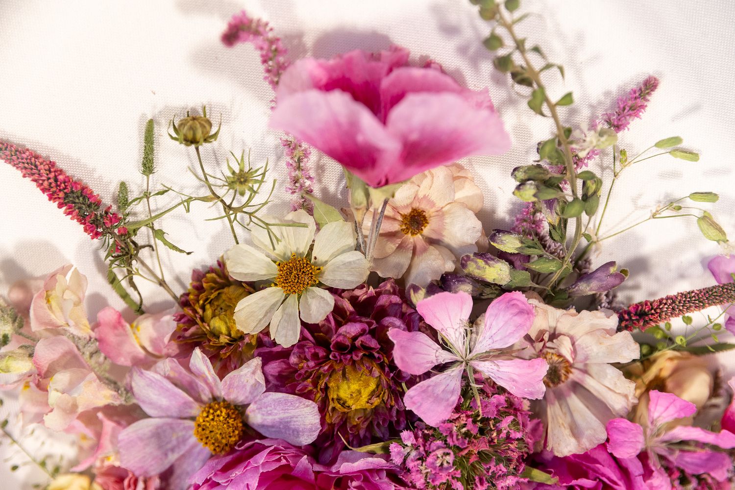 A vibrant bouquet of pink, white, and magenta wildflowers including daisies and cosmos arranged together.