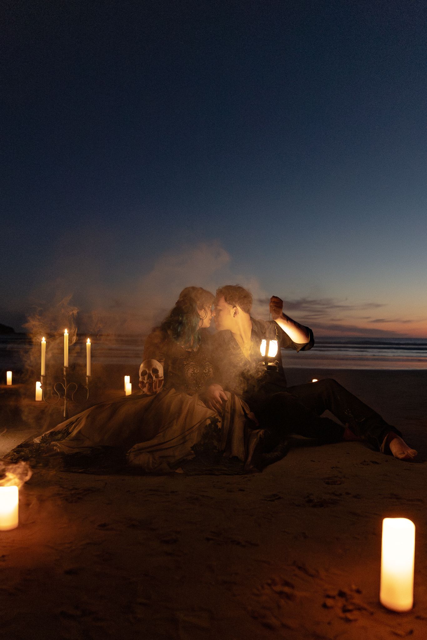 Couple sharing a romantic moment on a candlelit Oregon Coast at dusk, surrounded by glowing candles.